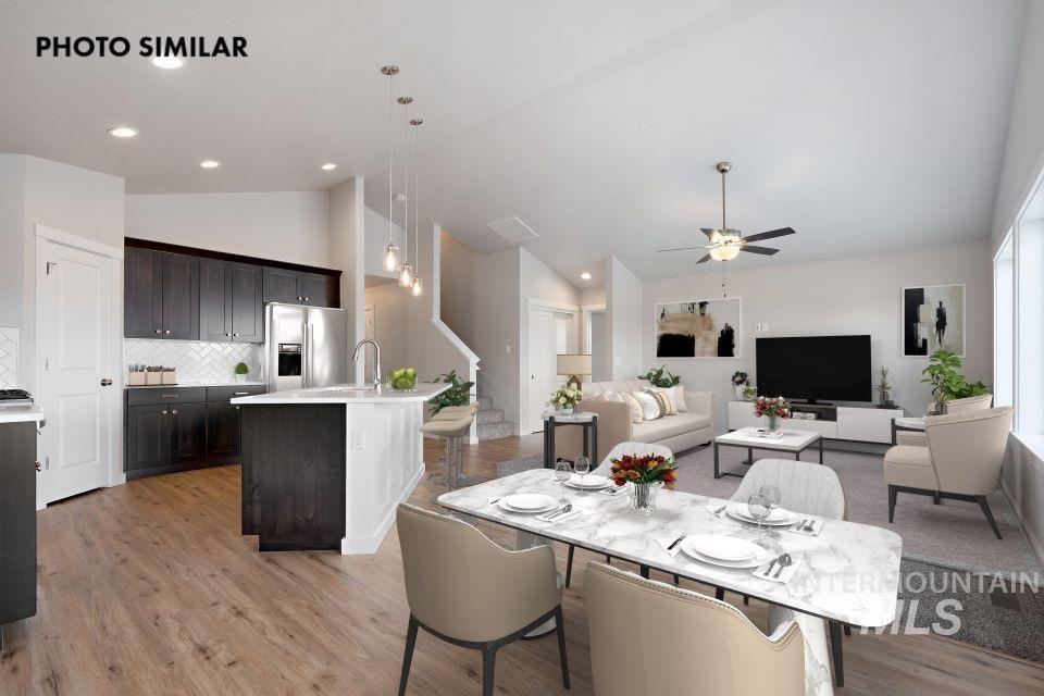 Open-concept interior featuring wood-finish flooring, a kitchen island with seating, dark wood cabinetry, and a white subway tile backsplash