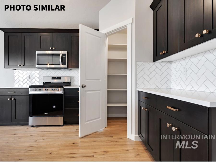 Kitchen featuring dark wood-finish cabinetry with brass hardware, white countertops, and a white herringbone tile backsplash