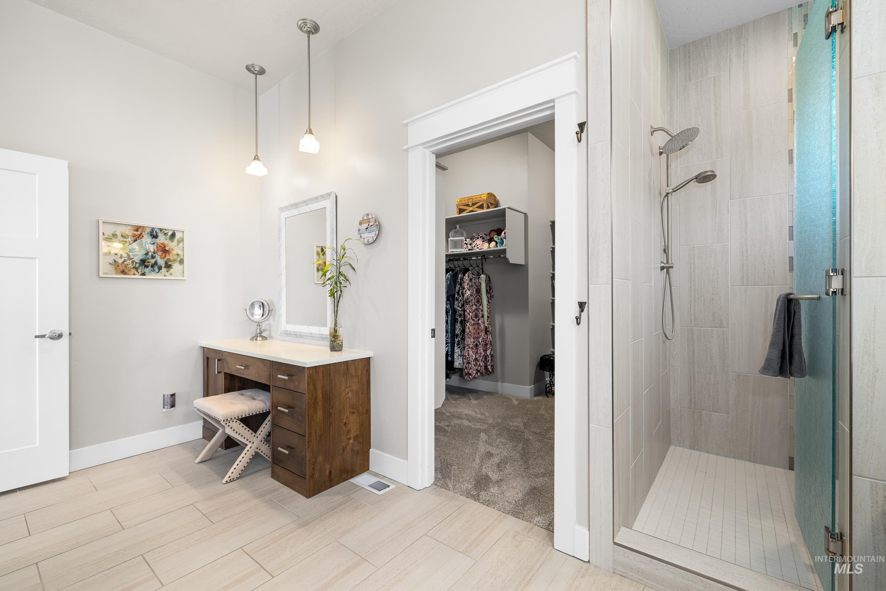 Bathroom with a stall shower, vanity, a walk in closet, and wood finished floors