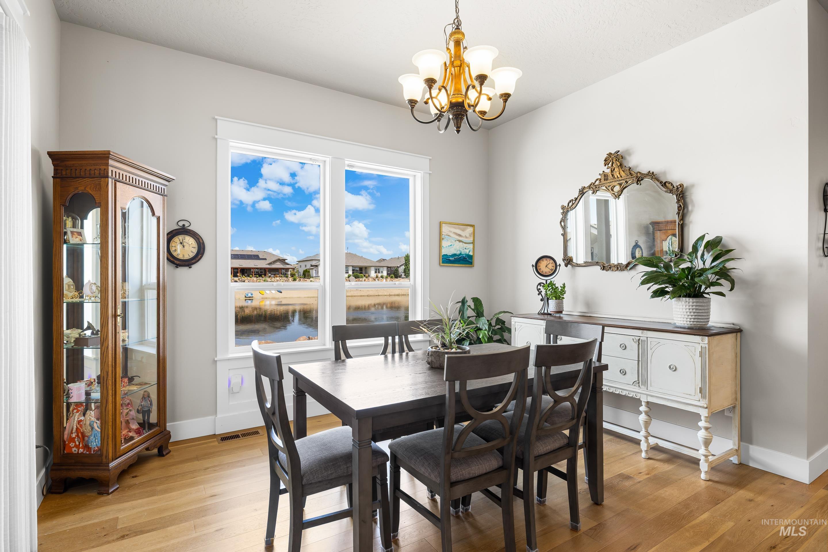 Dining room featuring a chandelier, light wood-type flooring, and a water view
