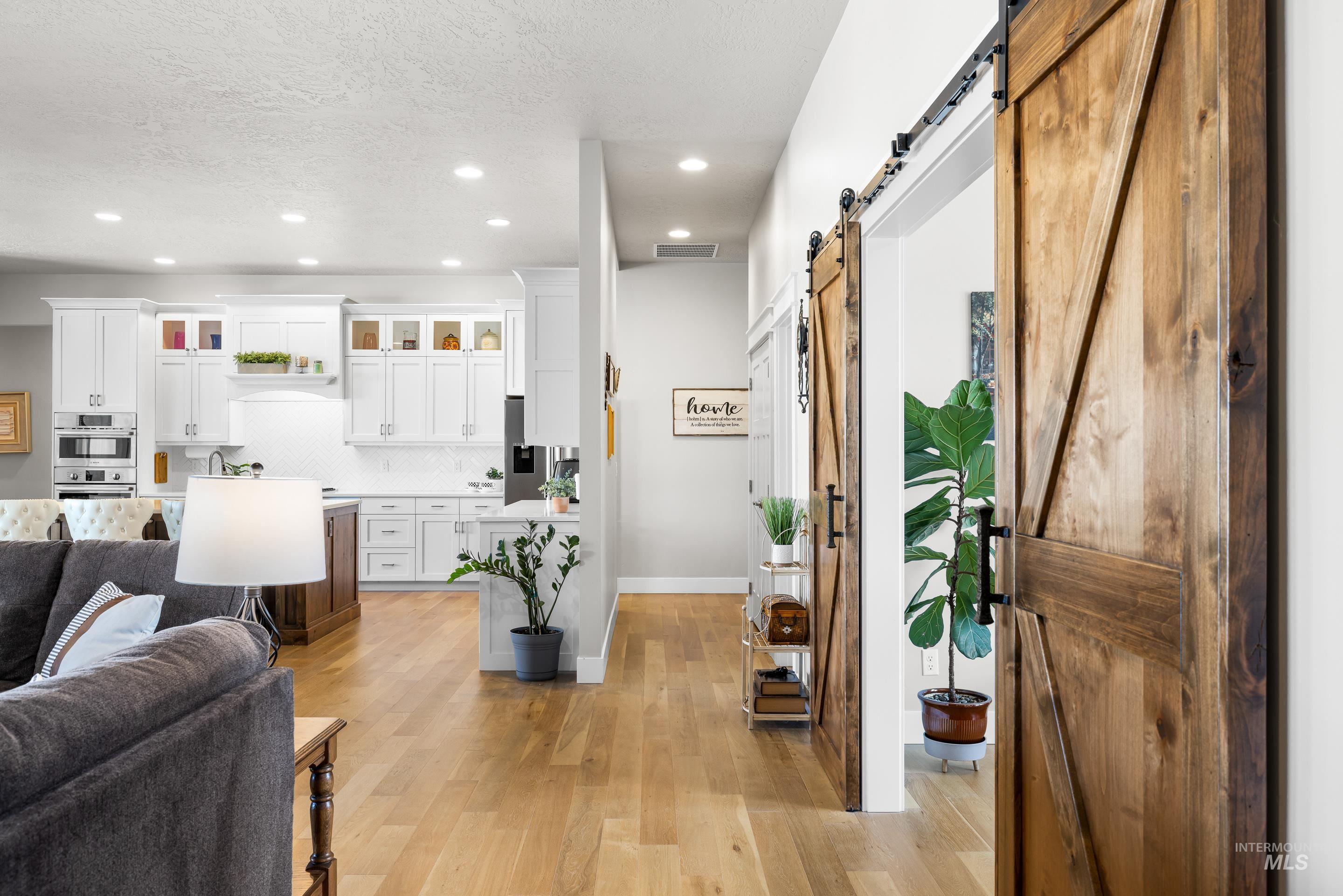 Living area with a barn door, light wood-type flooring, recessed lighting, and a textured ceiling