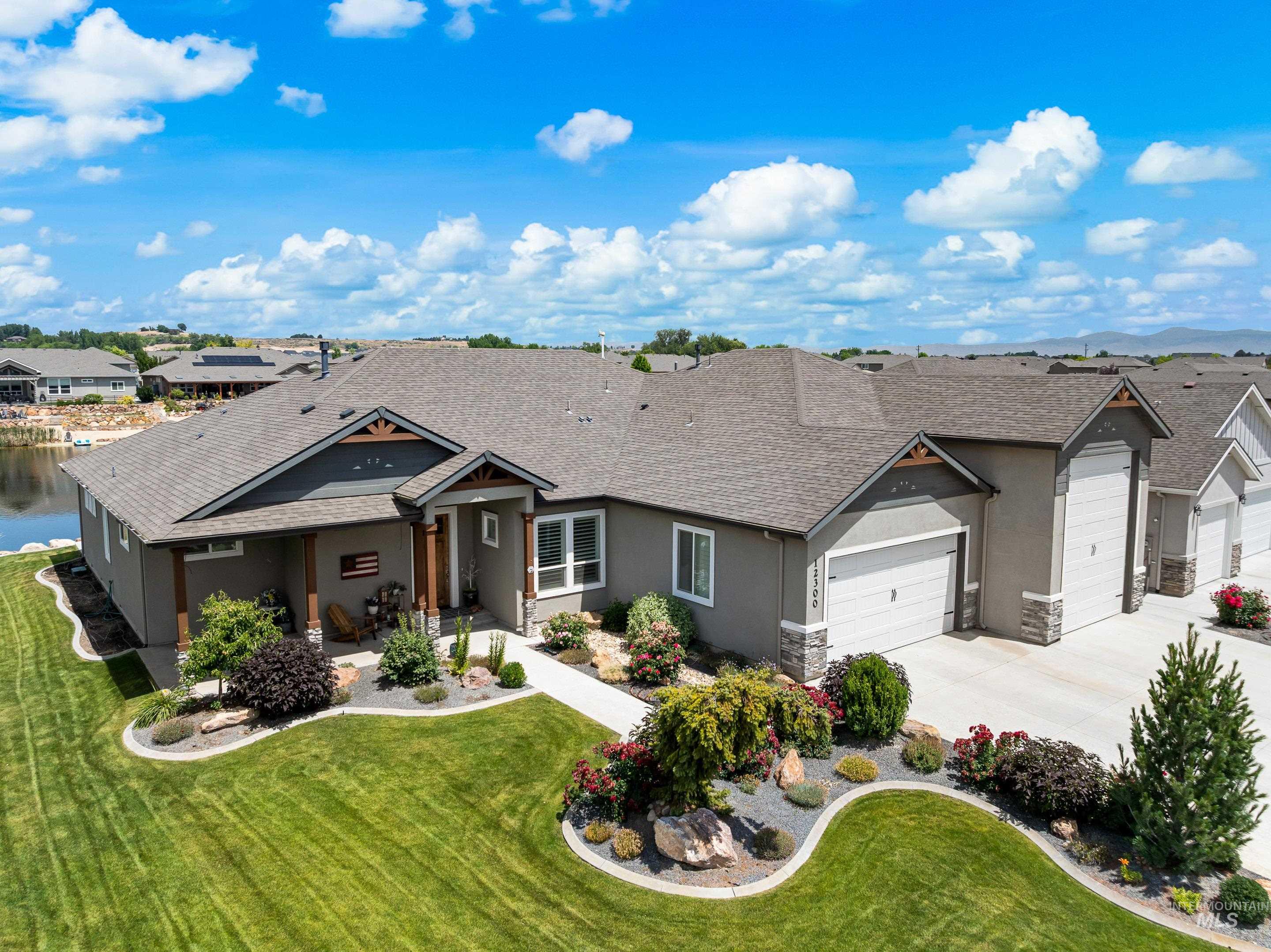 View of front facade featuring an attached garage, stucco siding, driveway, a residential view, and a front lawn