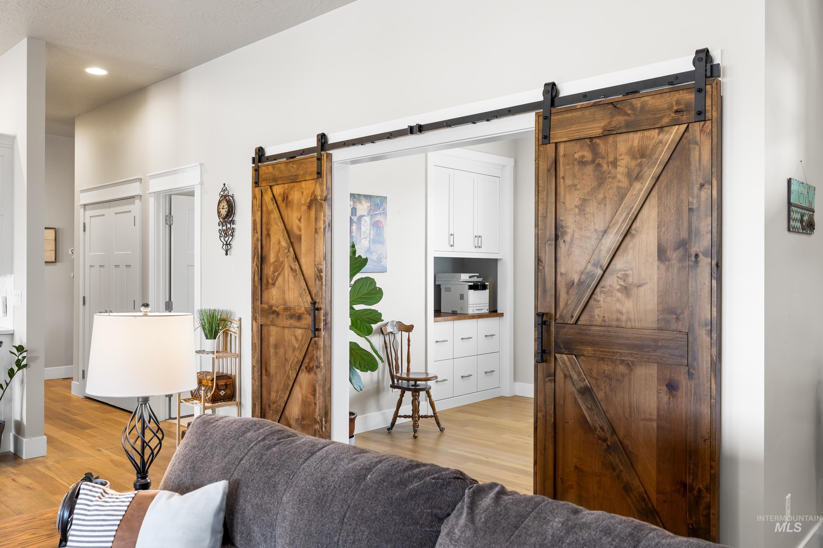 Living room featuring a barn door, light wood-type flooring, and recessed lighting