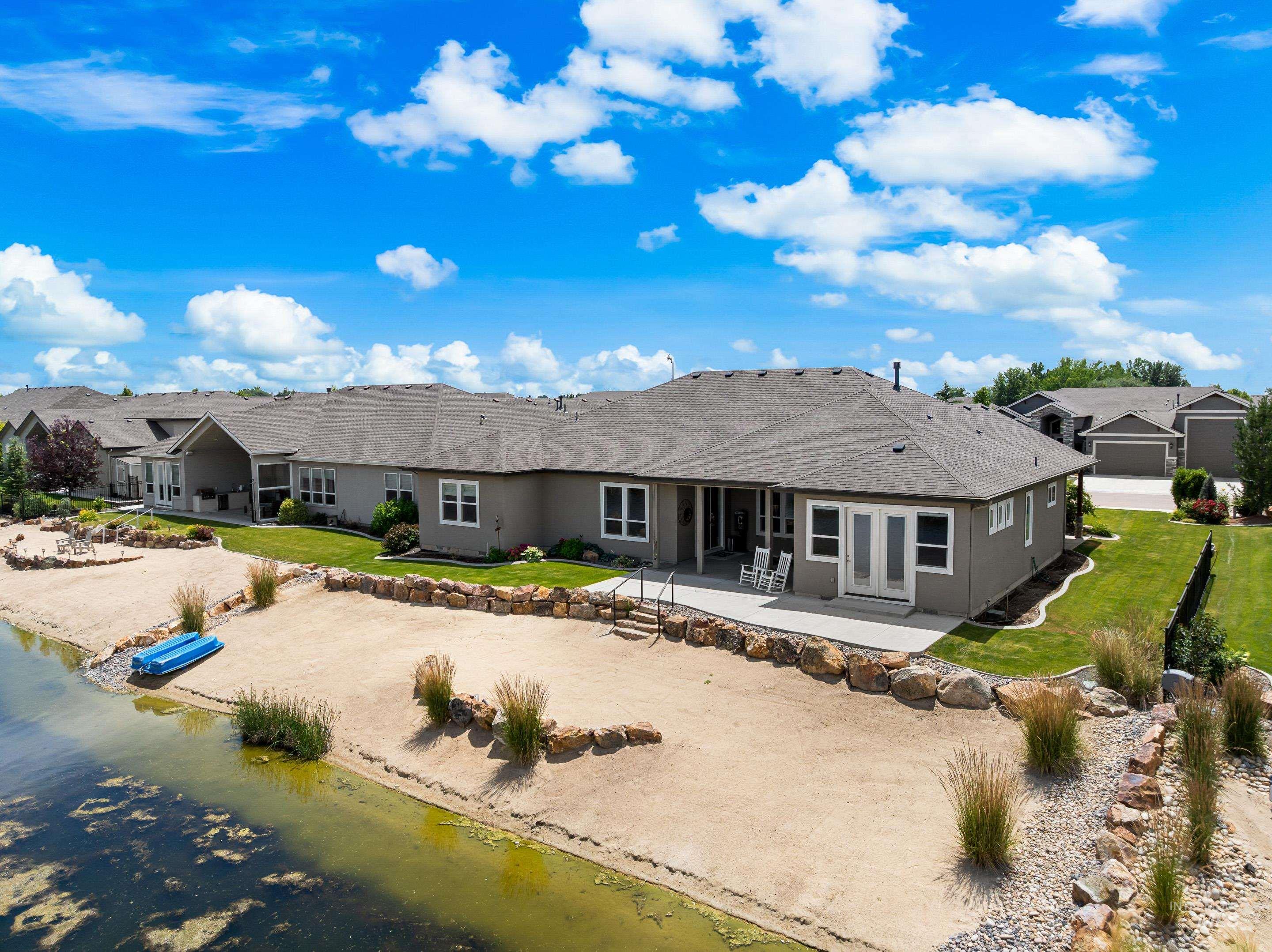 Back of house with a patio area, a water view, a lawn, and a shingled roof