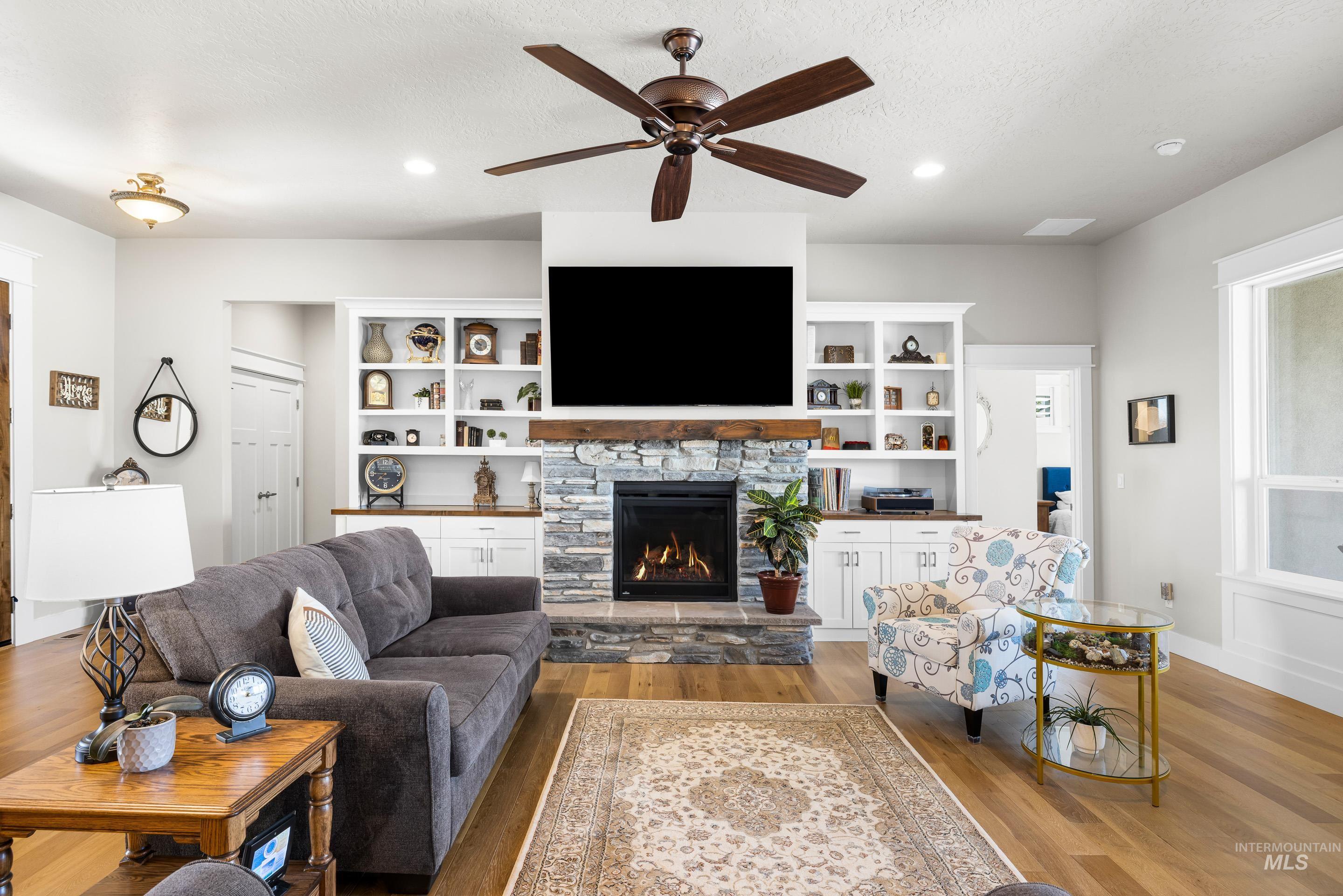 Living room featuring wood finished floors, a fireplace, a ceiling fan, recessed lighting, and a textured ceiling