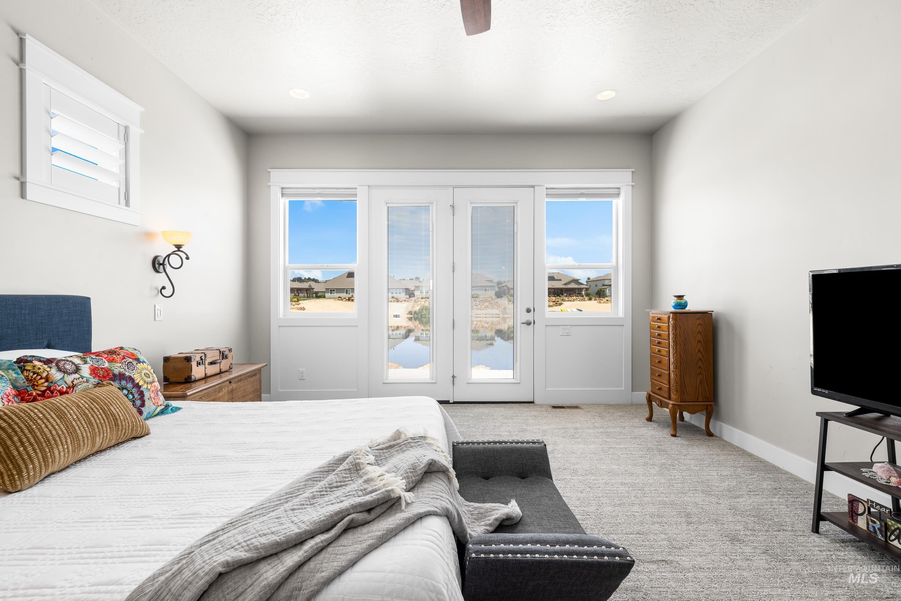 Carpeted bedroom featuring access to exterior, multiple windows, and ceiling fan