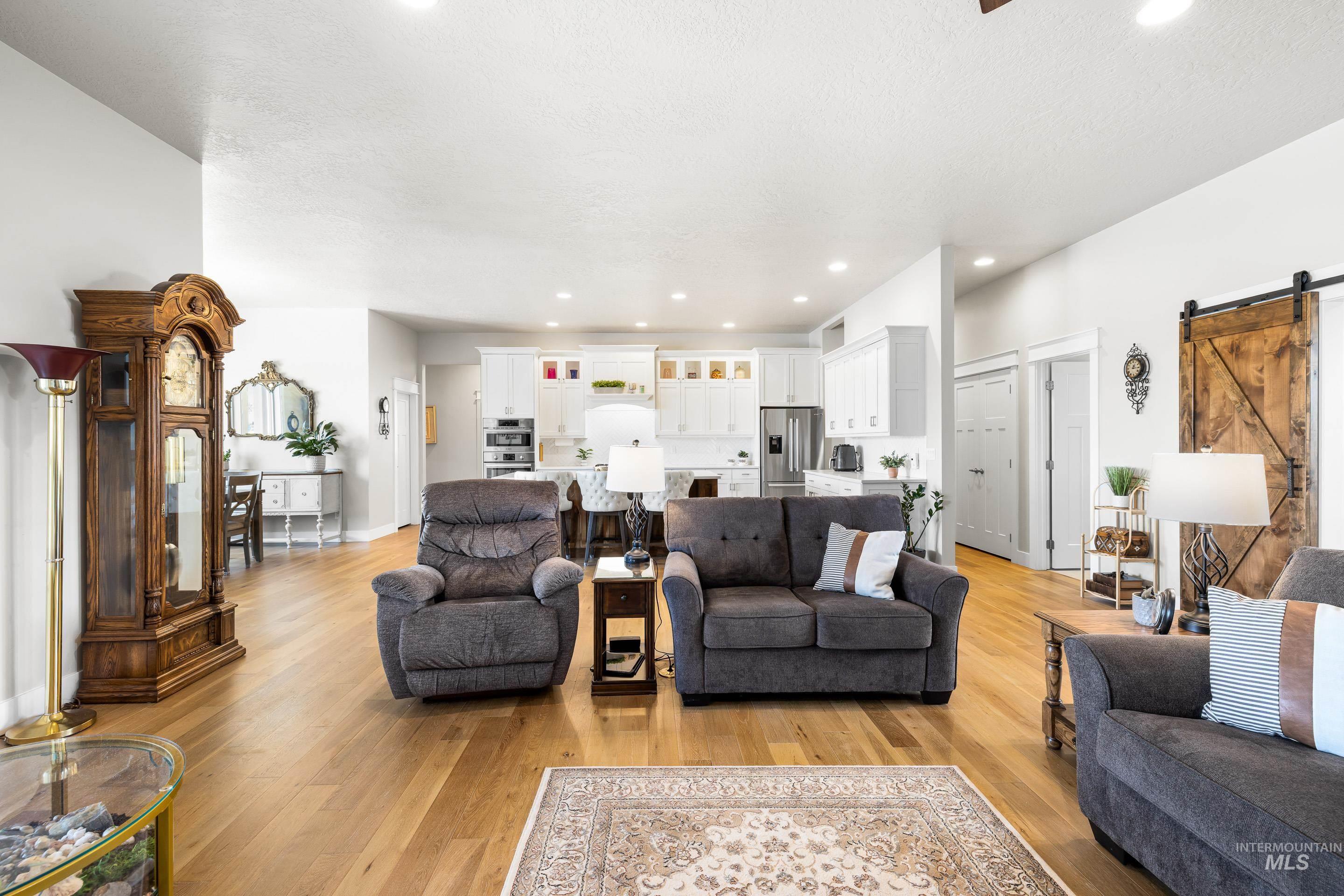 Living room with a barn door, light wood-style flooring, recessed lighting, and a textured ceiling
