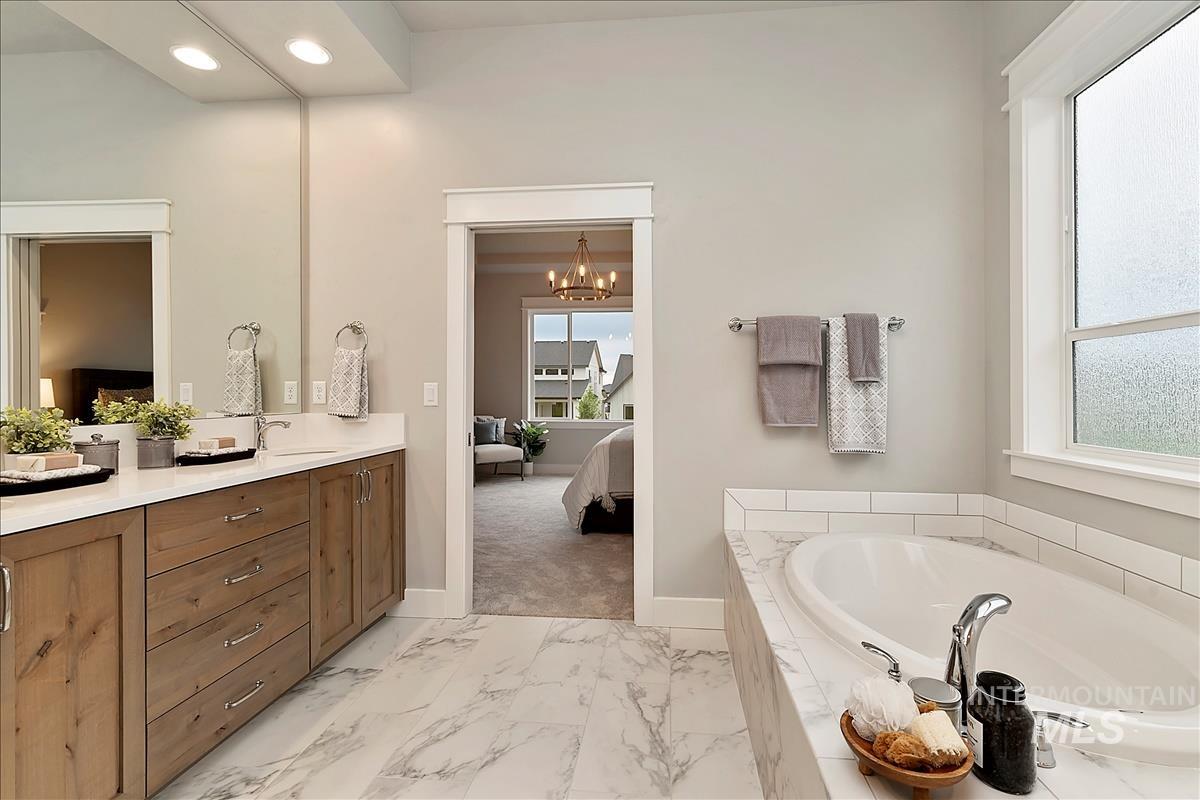 Bathroom with connected bathroom, light marble finish floors, a garden tub, double vanity, and hanging lights