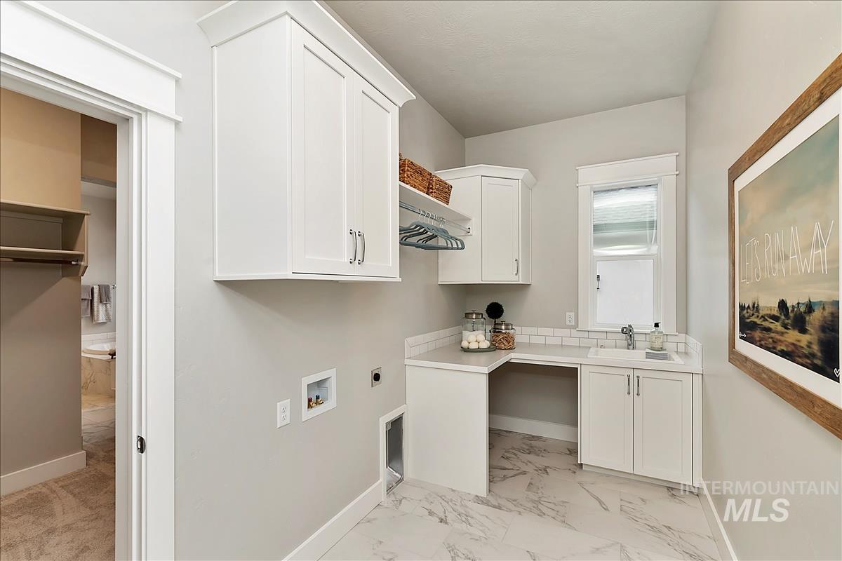 Laundry room with hookup for an electric dryer, light marble finish flooring, cabinet space, and hookup for a washing machine