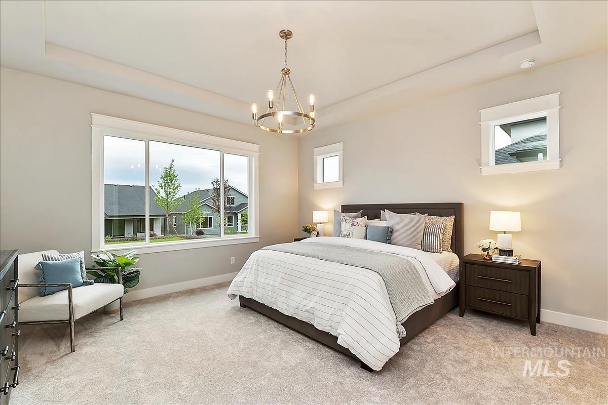 Carpeted bedroom with a tray ceiling and a chandelier