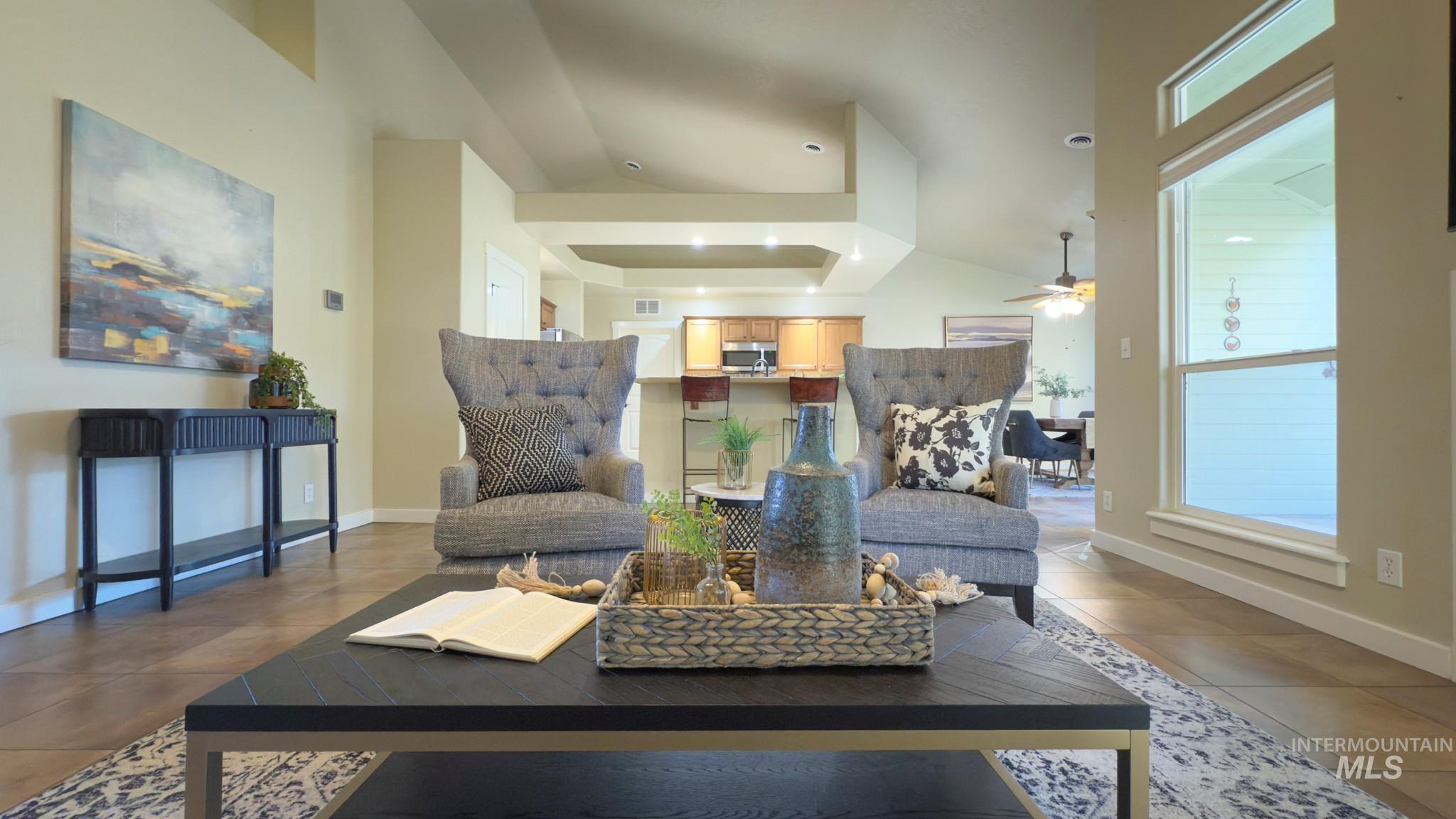 Living room featuring dark tile patterned floors, a raised ceiling, and ceiling fan