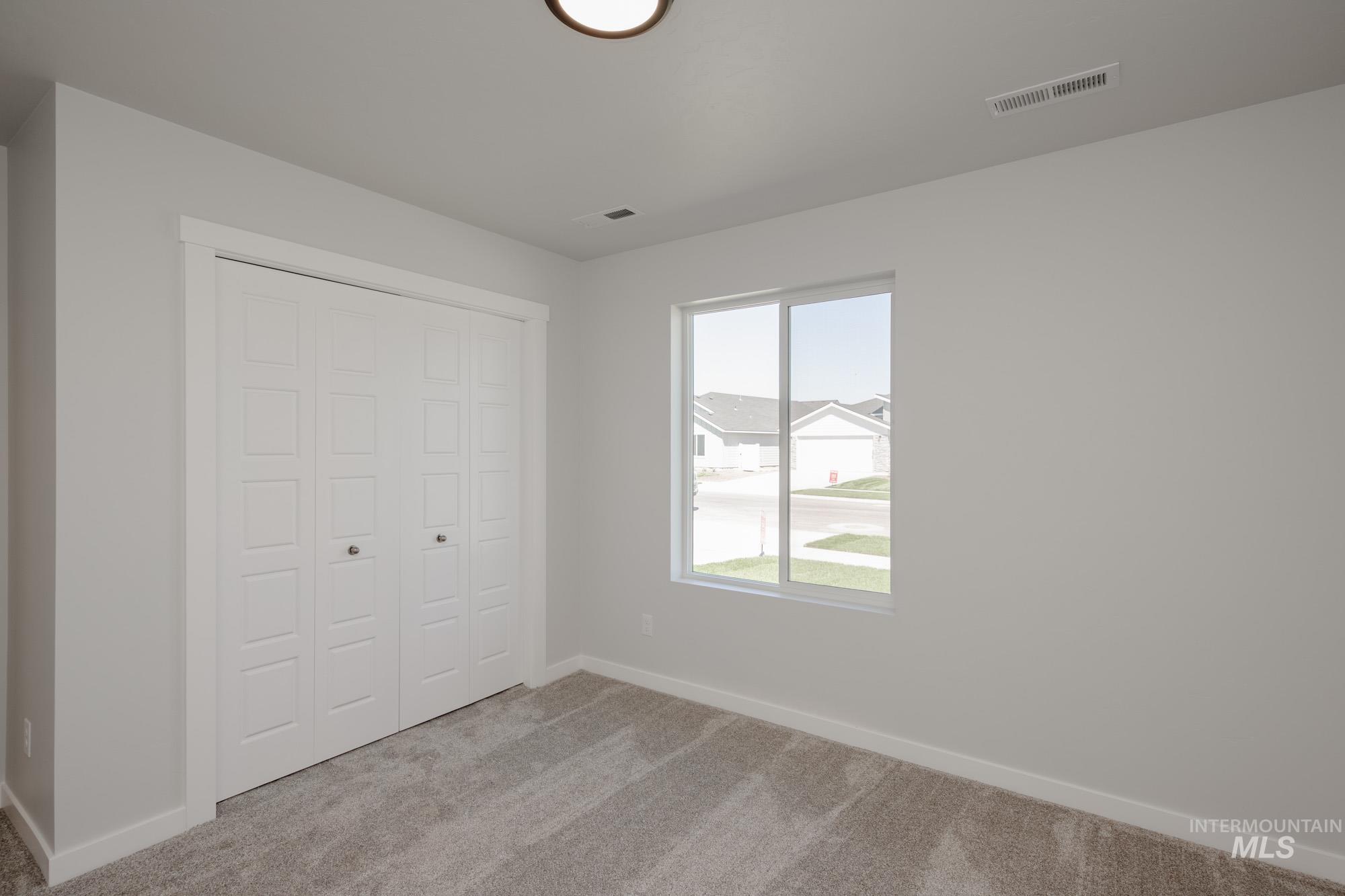 Unfurnished bedroom with light carpet and a closet