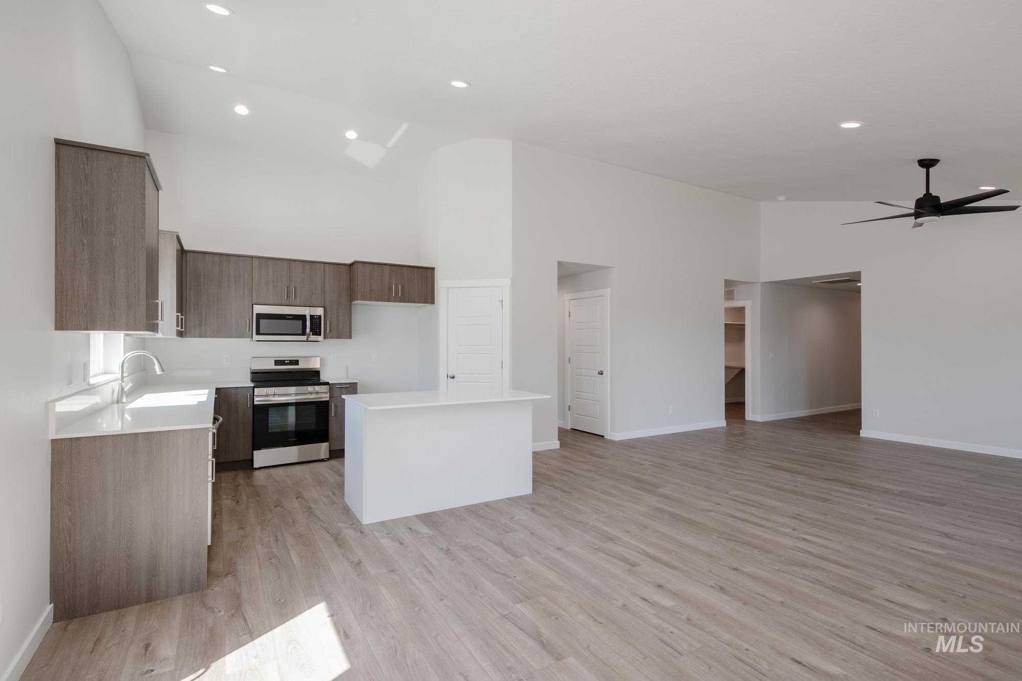Kitchen featuring a center island, modern cabinets, appliances with stainless steel finishes, high vaulted ceiling, and open floor plan