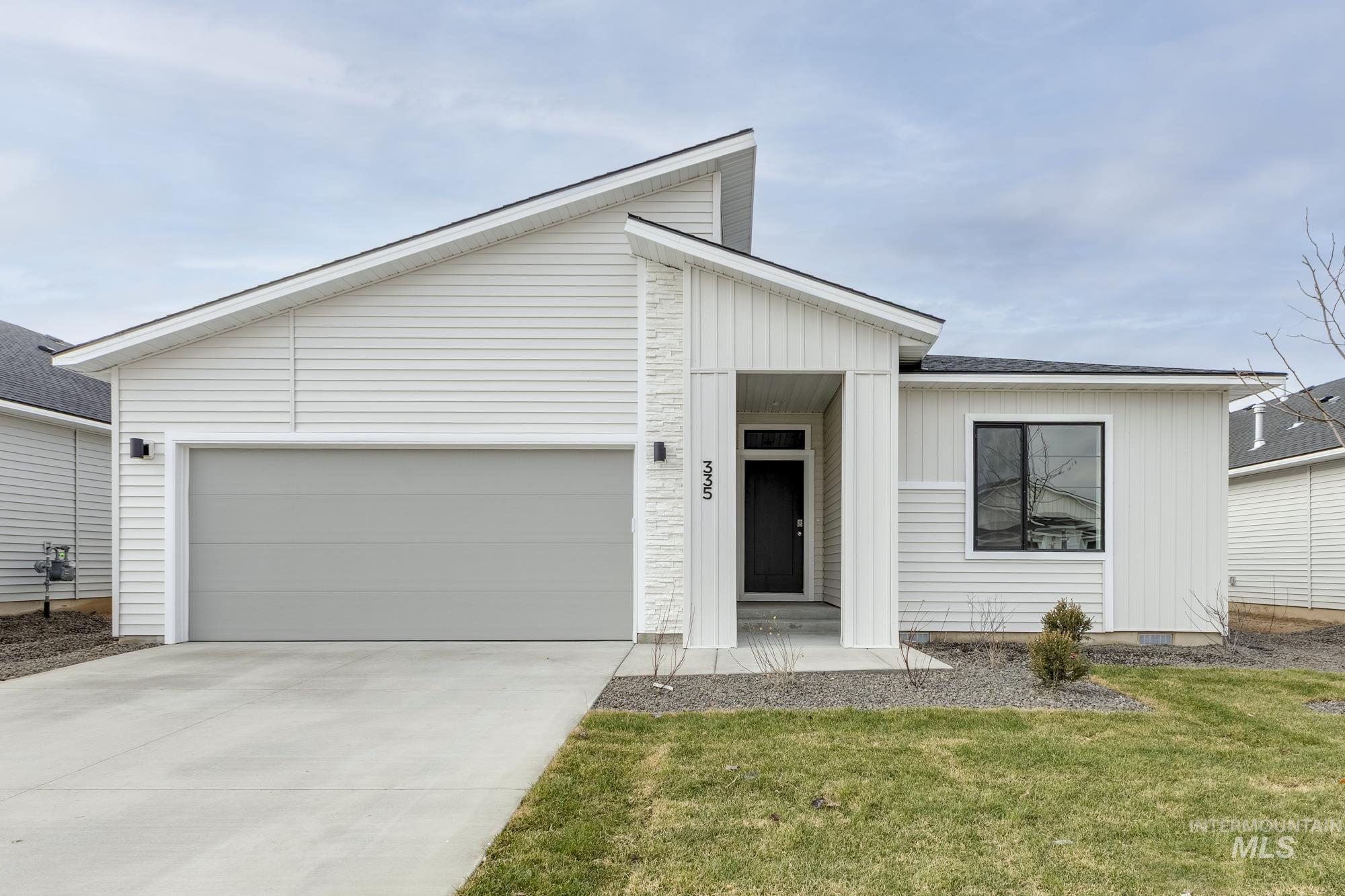 View of front of home with concrete driveway, a garage, a front lawn, and board and batten siding