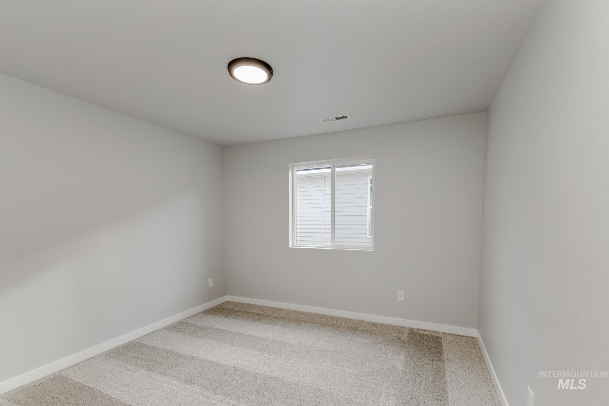 Empty room featuring light carpet and baseboards