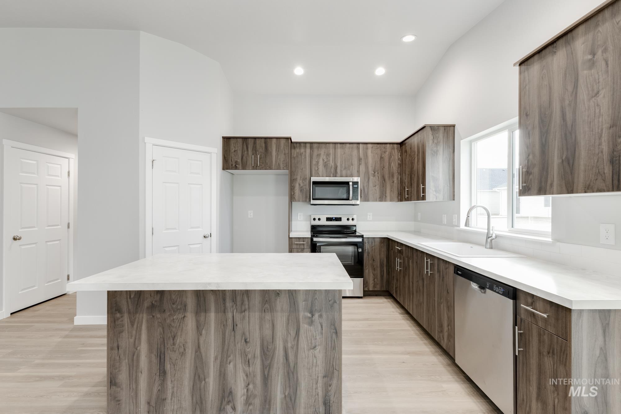 Kitchen with modern cabinets, appliances with stainless steel finishes, light countertops, a center island, and recessed lighting