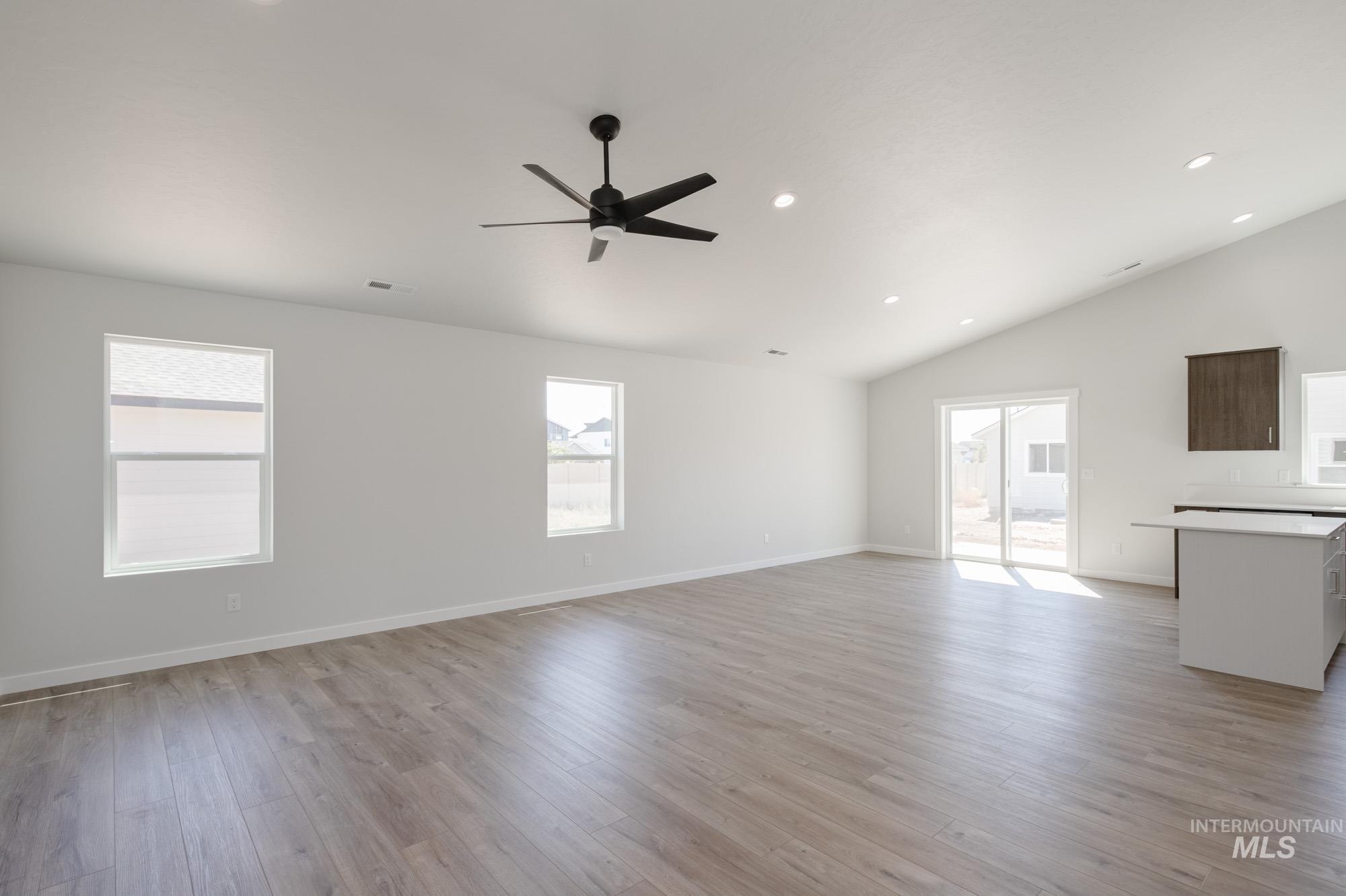 Unfurnished living room featuring light wood-style floors, recessed lighting, ceiling fan, and high vaulted ceiling