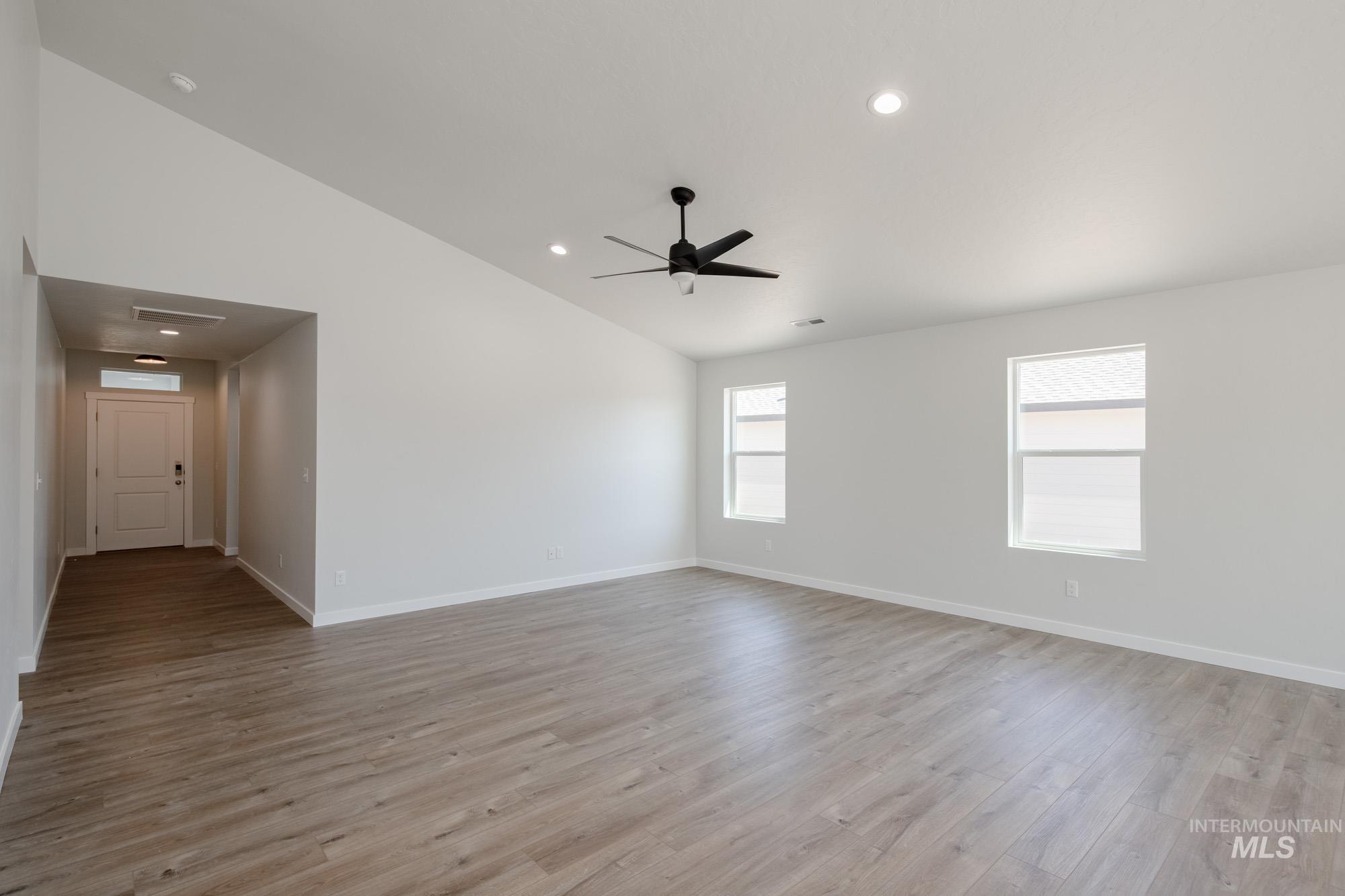 Empty room featuring vaulted ceiling, recessed lighting, light wood-style flooring, and ceiling fan