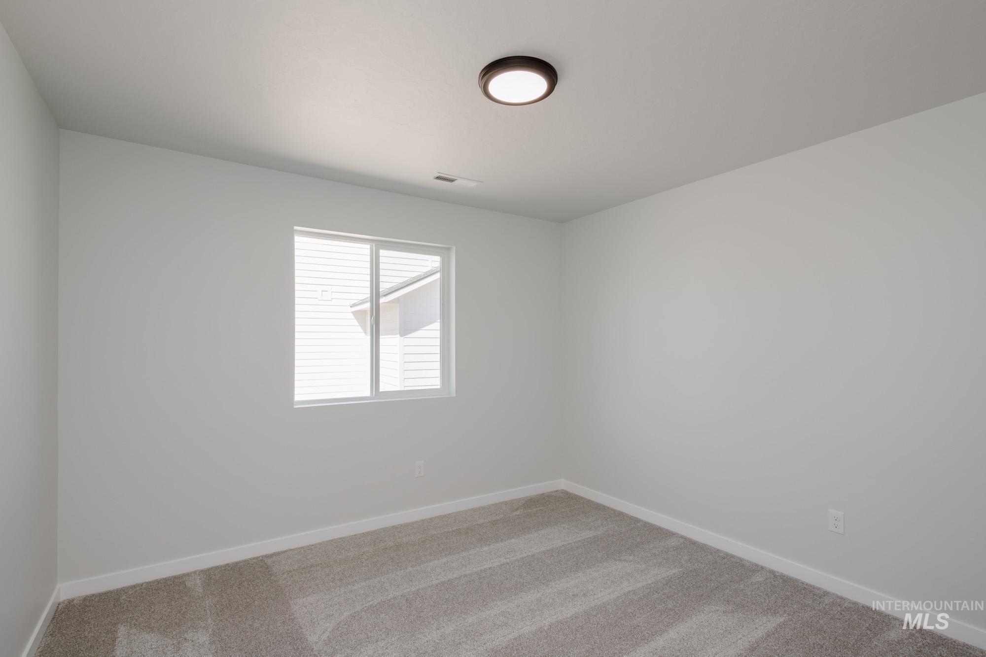 Unfurnished room featuring light carpet and baseboards