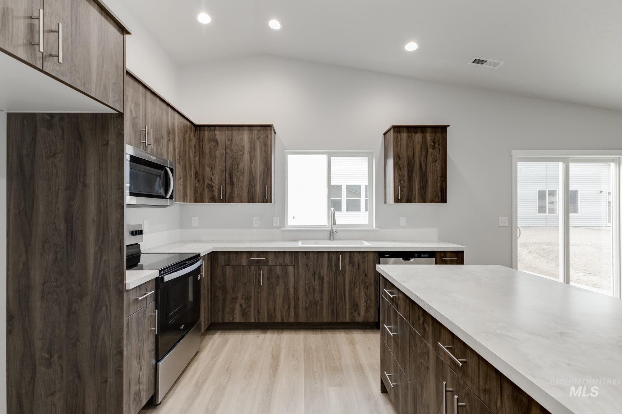 Kitchen with appliances with stainless steel finishes, modern cabinets, light countertops, dark brown cabinetry, and recessed lighting