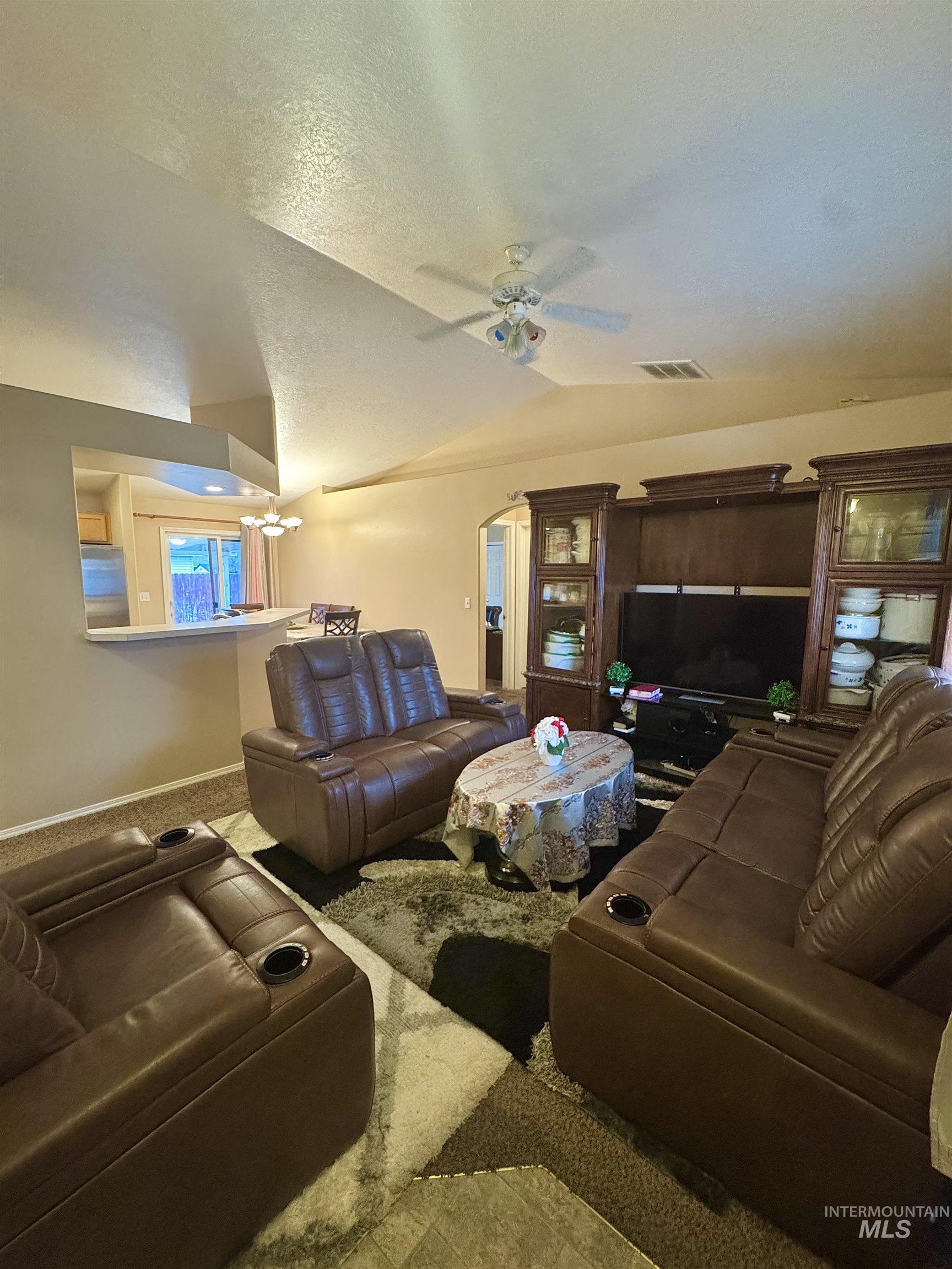 Carpeted living room featuring ceiling fan and baseboards