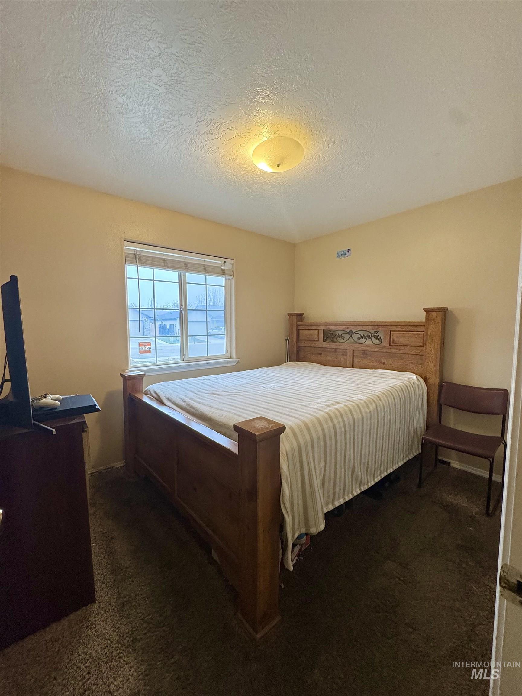 Bedroom with dark colored carpet and a textured ceiling