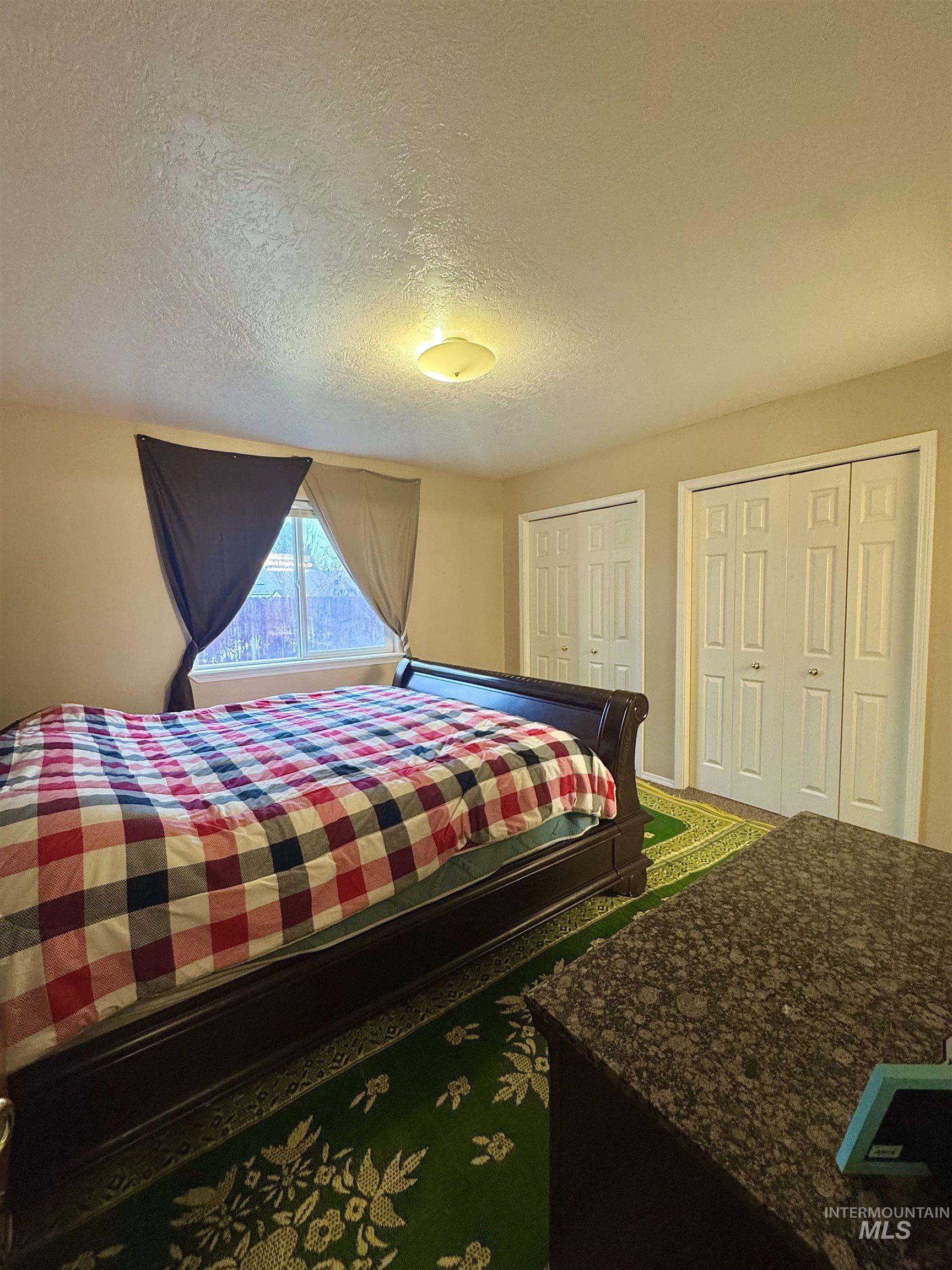 Bedroom with a textured ceiling and multiple closets