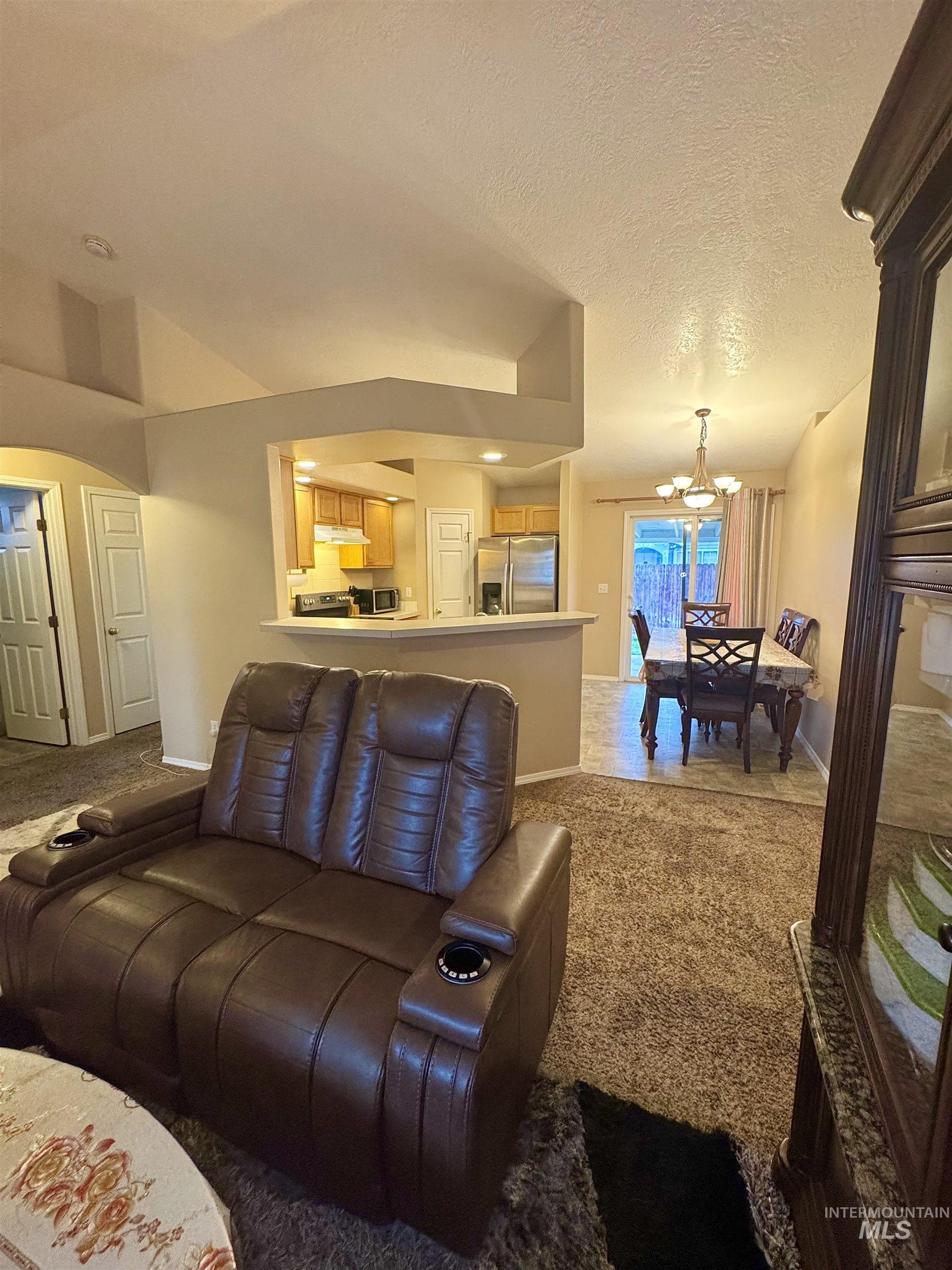 Living room with light carpet, suspended lighting, and a textured ceiling