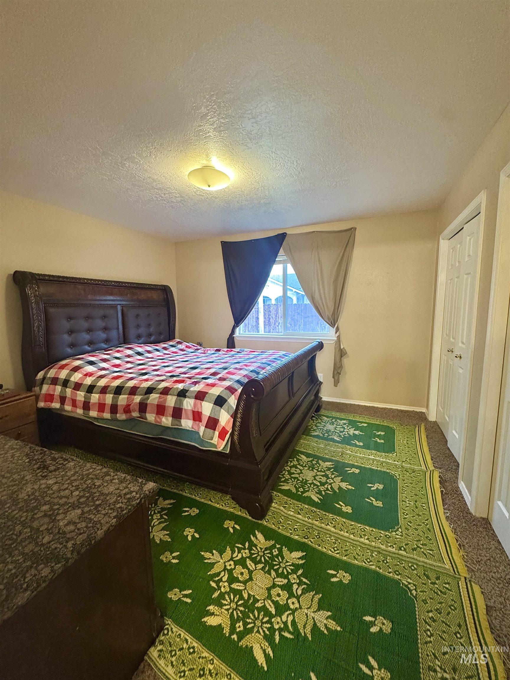 Bedroom featuring a textured ceiling, carpet flooring, and a closet
