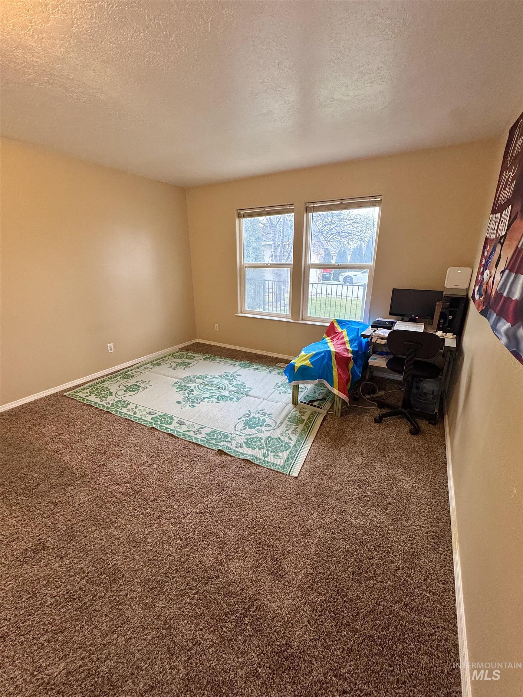 Playroom featuring a textured ceiling, carpet floors, and a desk