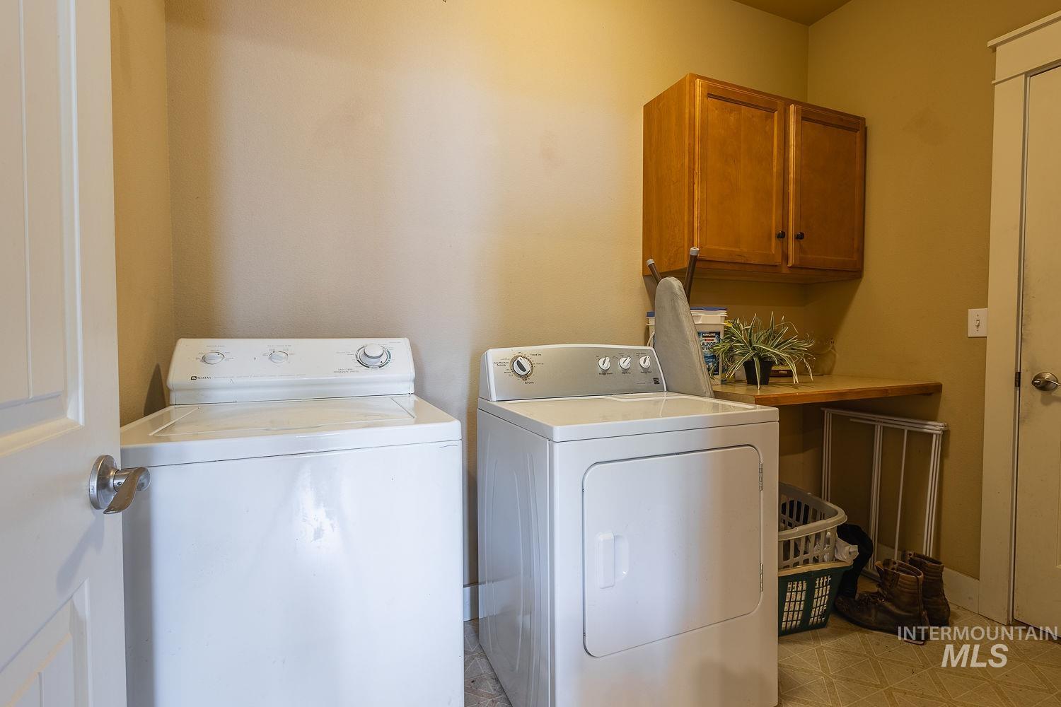 Washroom featuring cabinet space, washer and clothes dryer, and light flooring