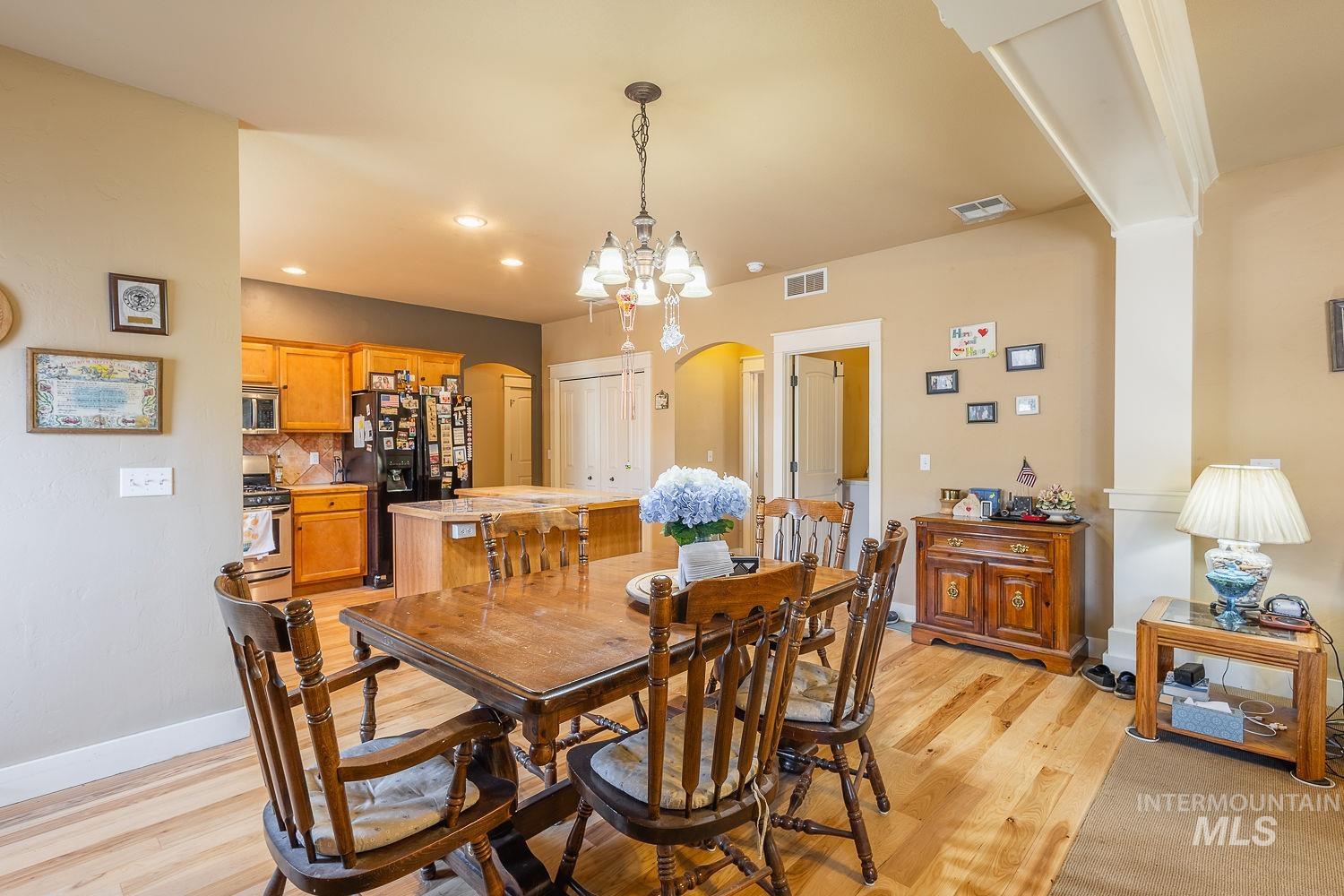 Dining area with arched walkways, light wood-type flooring, recessed lighting, and a chandelier