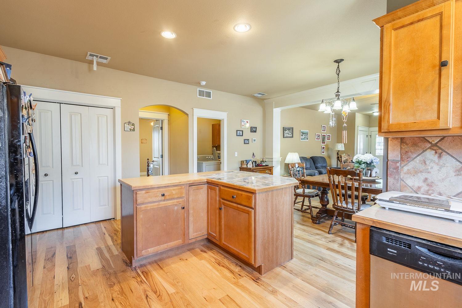 Kitchen with dishwasher, black fridge with ice dispenser, tasteful backsplash, arched walkways, and light countertops