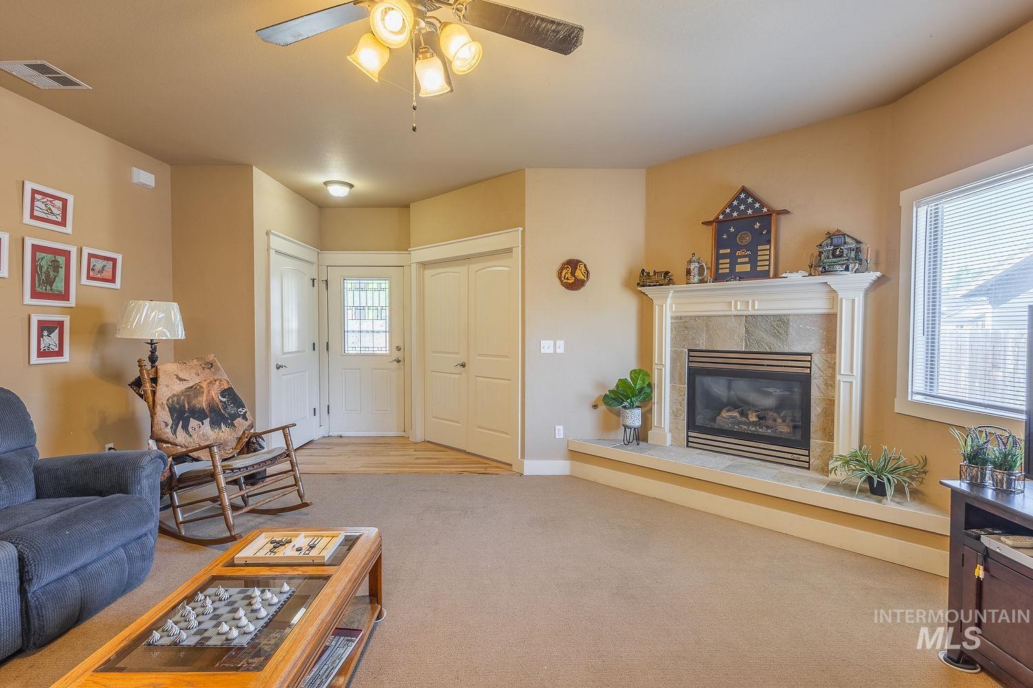 Carpeted living area with a ceiling fan and a fireplace