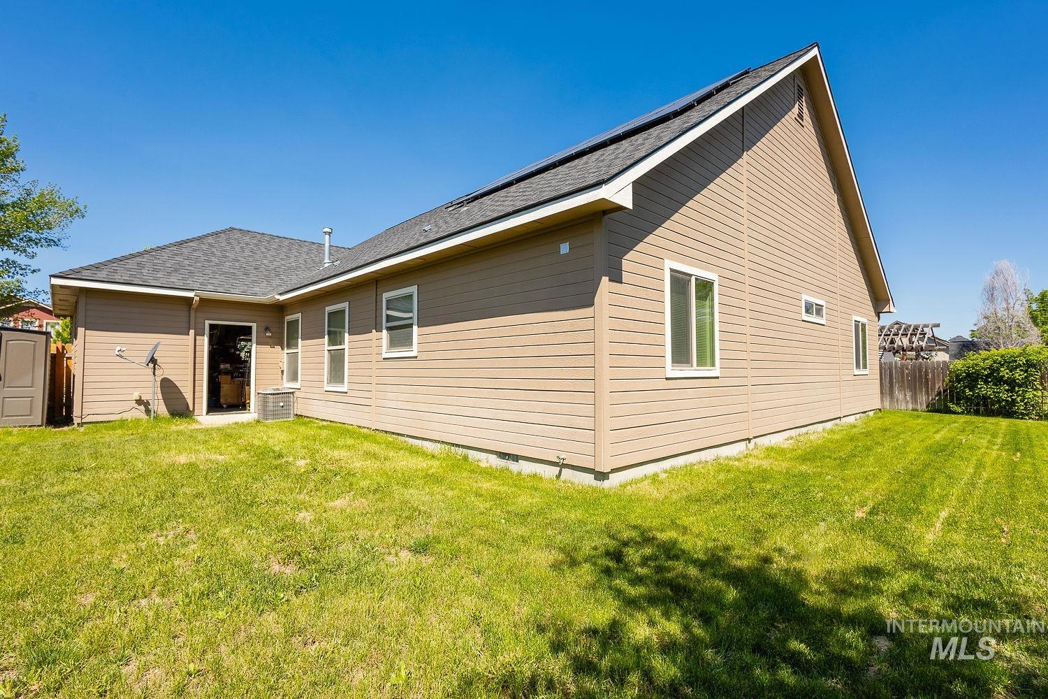 Back of property featuring roof with shingles and a storage shed