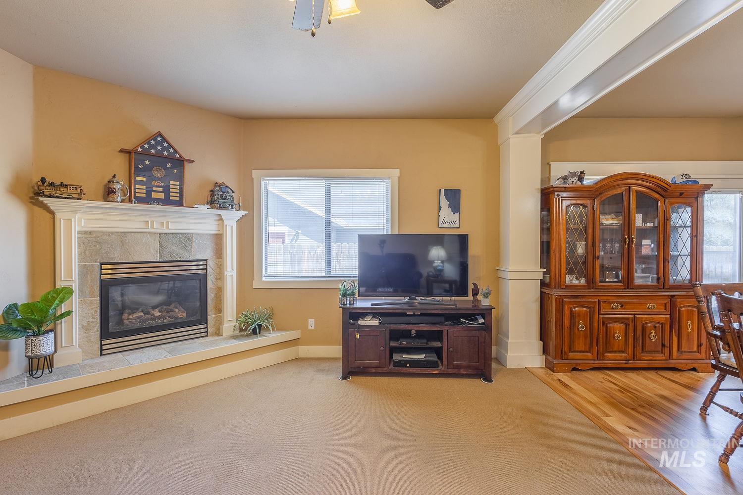 Carpeted living room featuring a tiled fireplace and wood finished floors