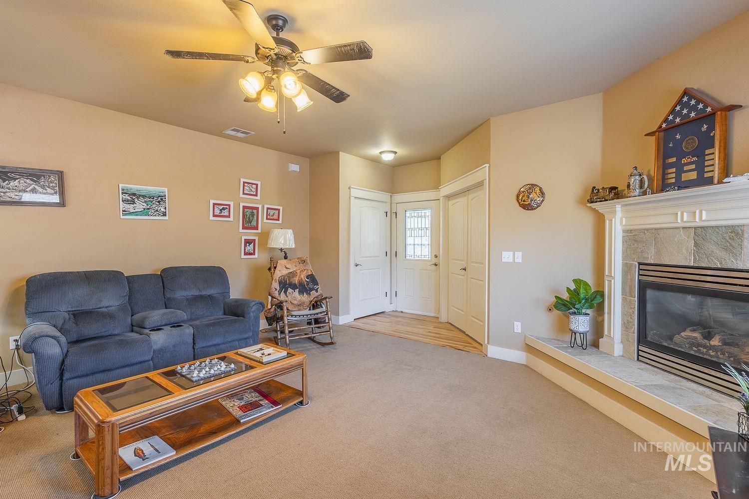 Carpeted living area featuring a ceiling fan and a high end fireplace