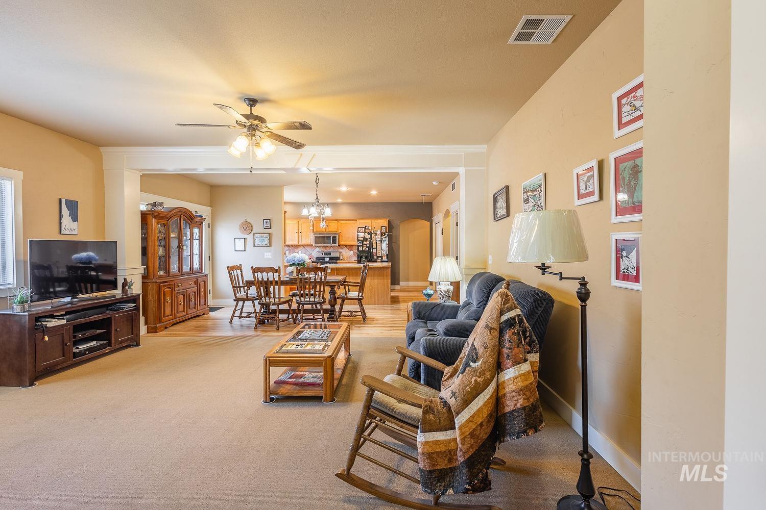 Living area featuring a ceiling fan, light carpet, and a chandelier
