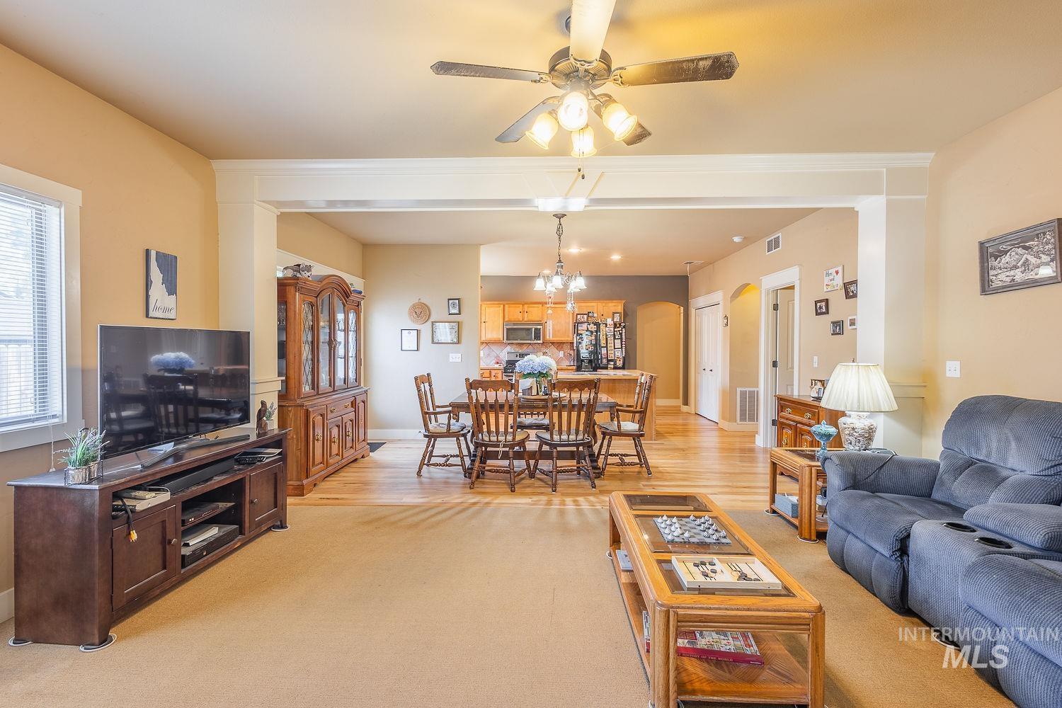 Living area with arched walkways, light colored carpet, and ceiling fan