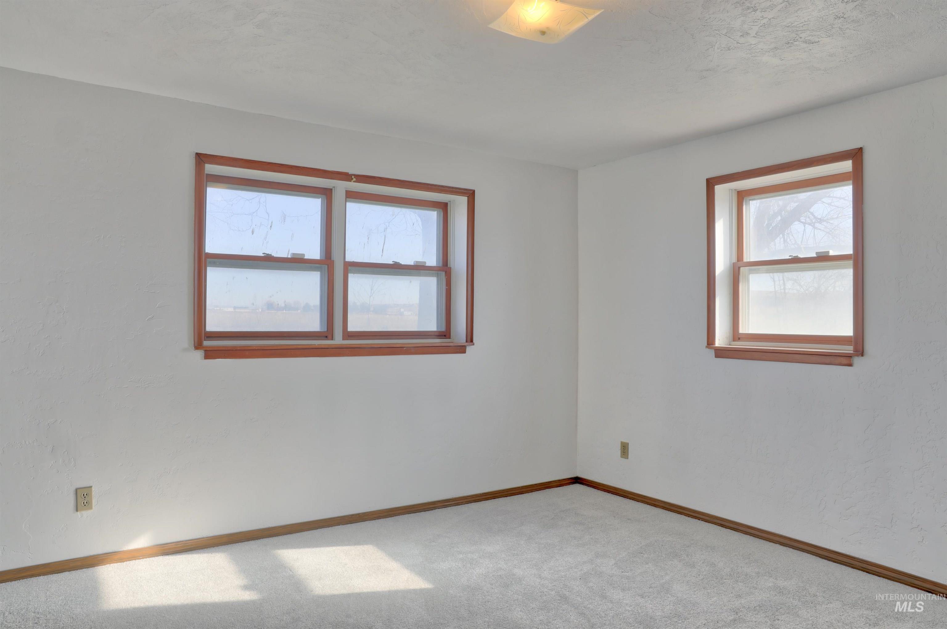Carpeted spare room featuring baseboards and a textured ceiling