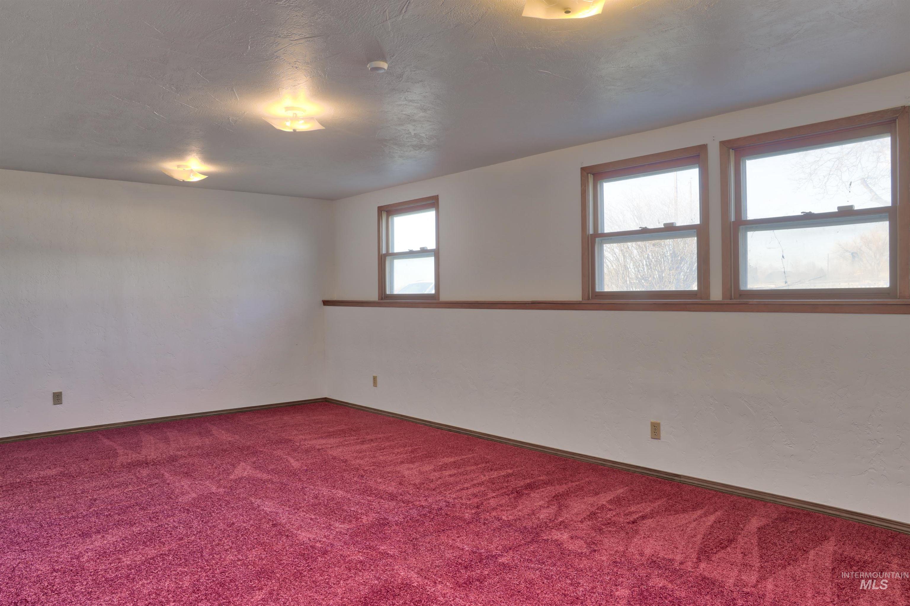 Carpeted spare room featuring baseboards