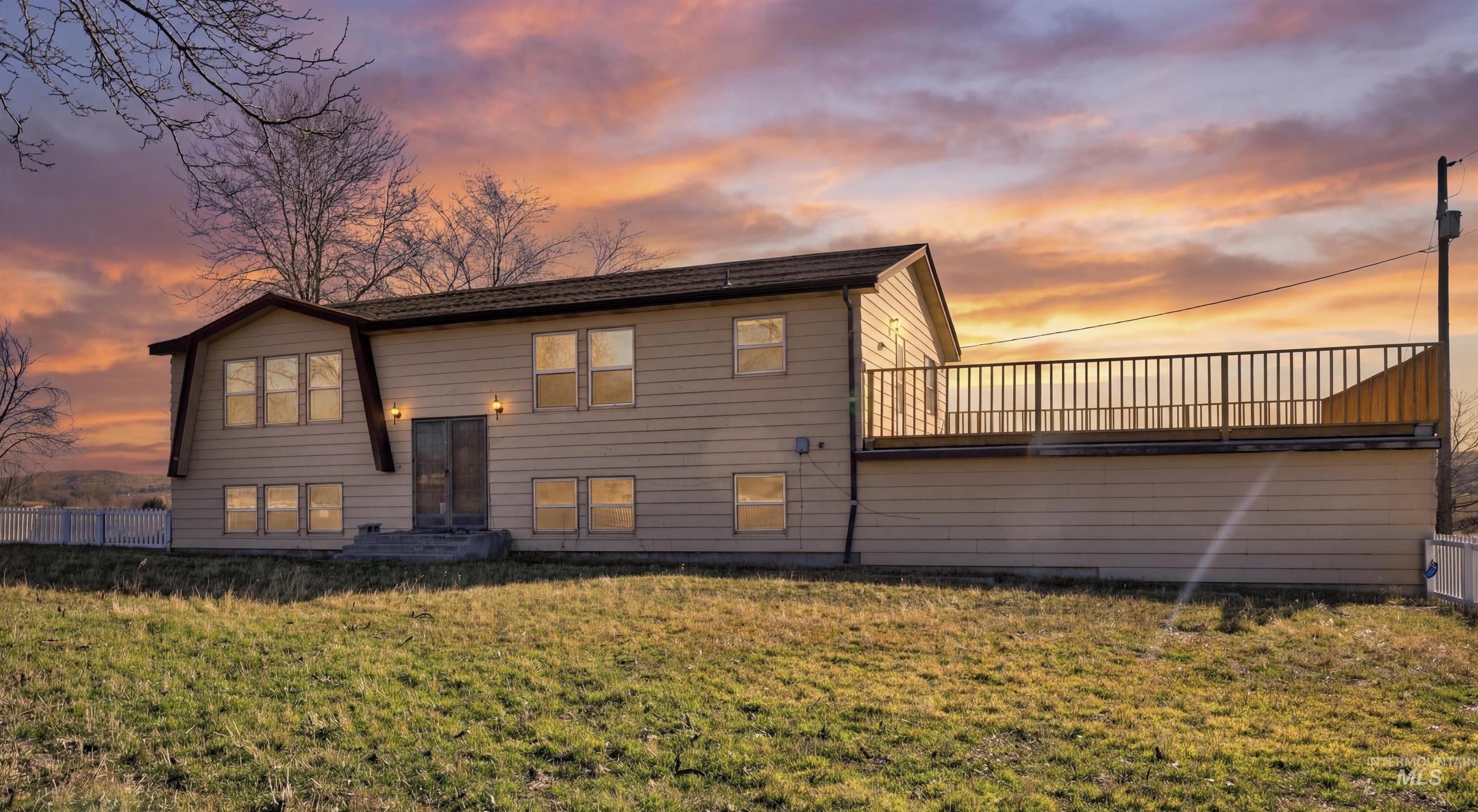Back of property at dusk with a lawn