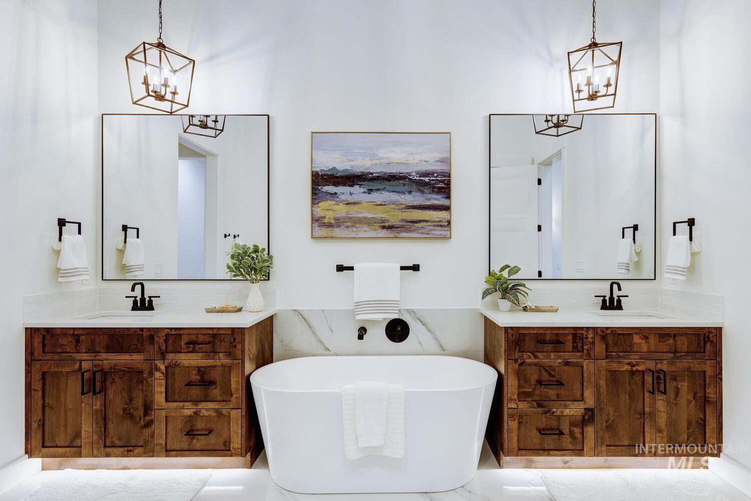 Bathroom with a chandelier, a freestanding tub, and two vanities
