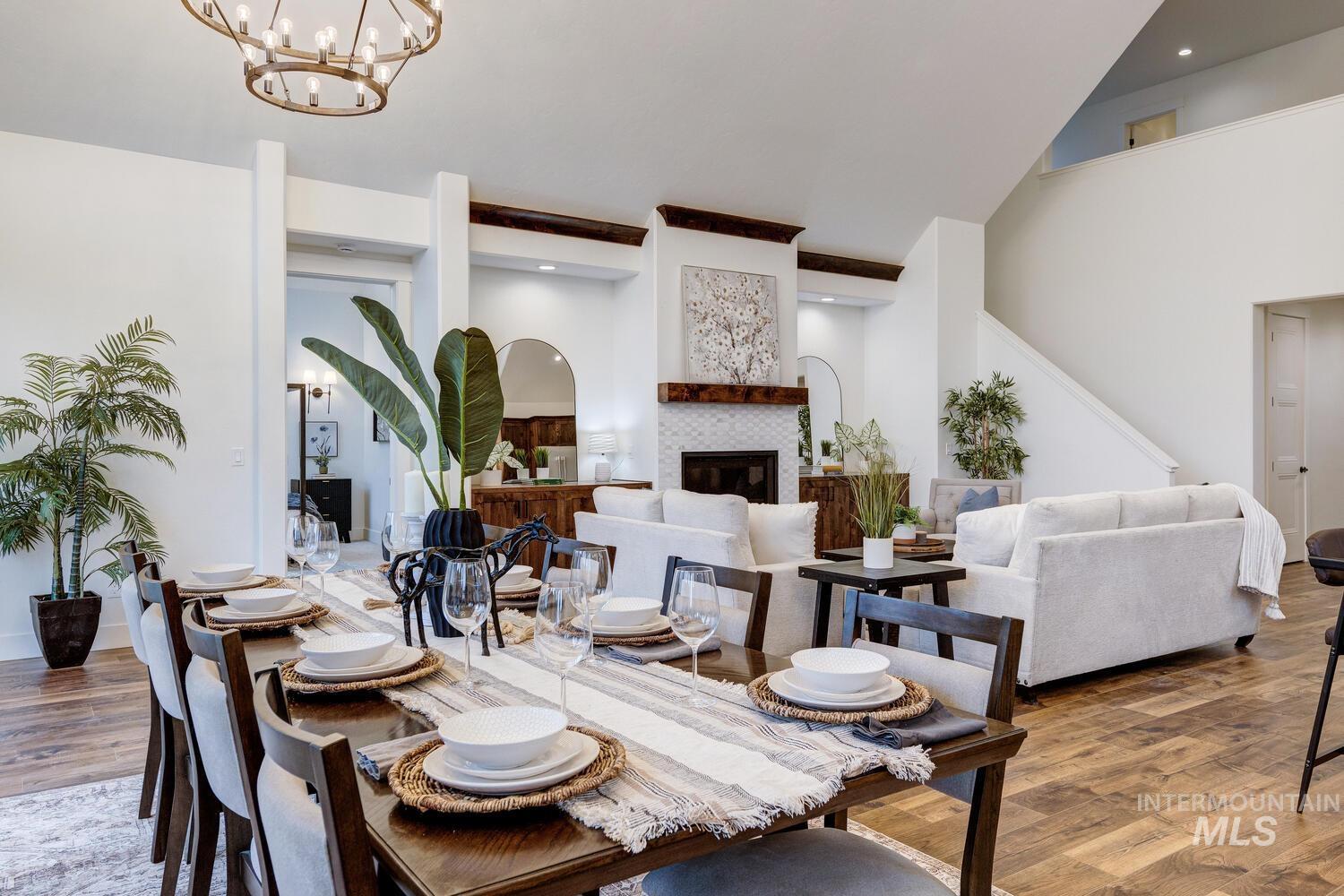Dining room with wood finished floors, a chandelier, a high ceiling, a fireplace, and stairway