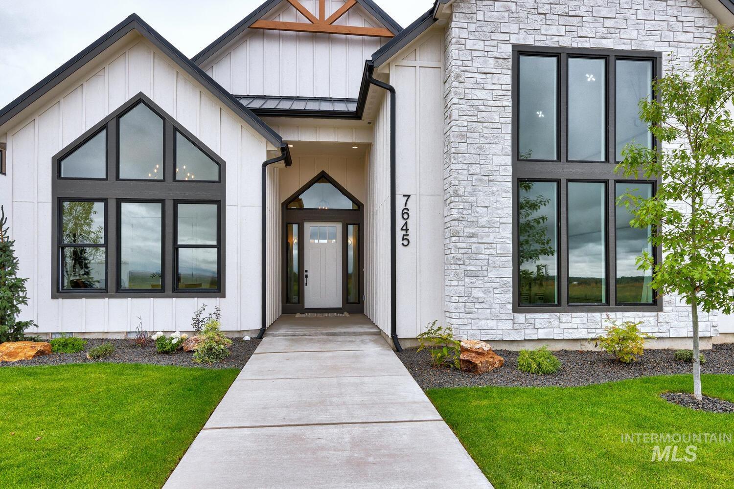 Entrance to property featuring stone siding, board and batten siding, a yard, and a metal roof