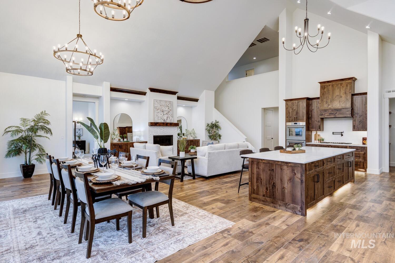 Dining room featuring a chandelier, light wood-type flooring, high vaulted ceiling, and a fireplace