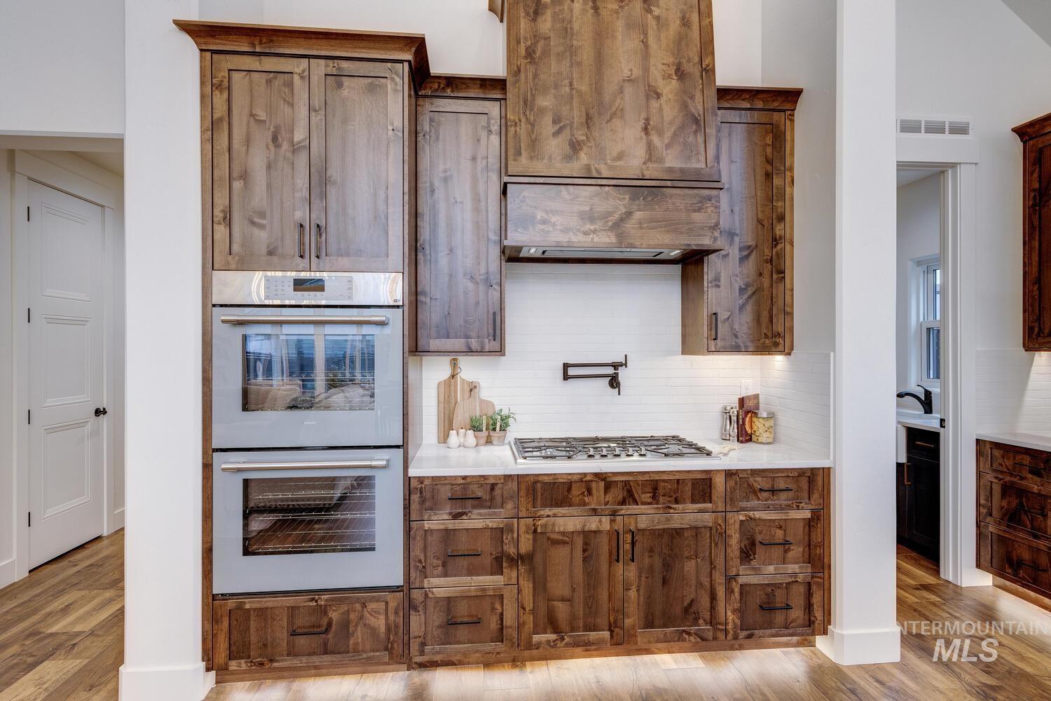 Kitchen with appliances with stainless steel finishes, light wood-type flooring, and tasteful backsplash