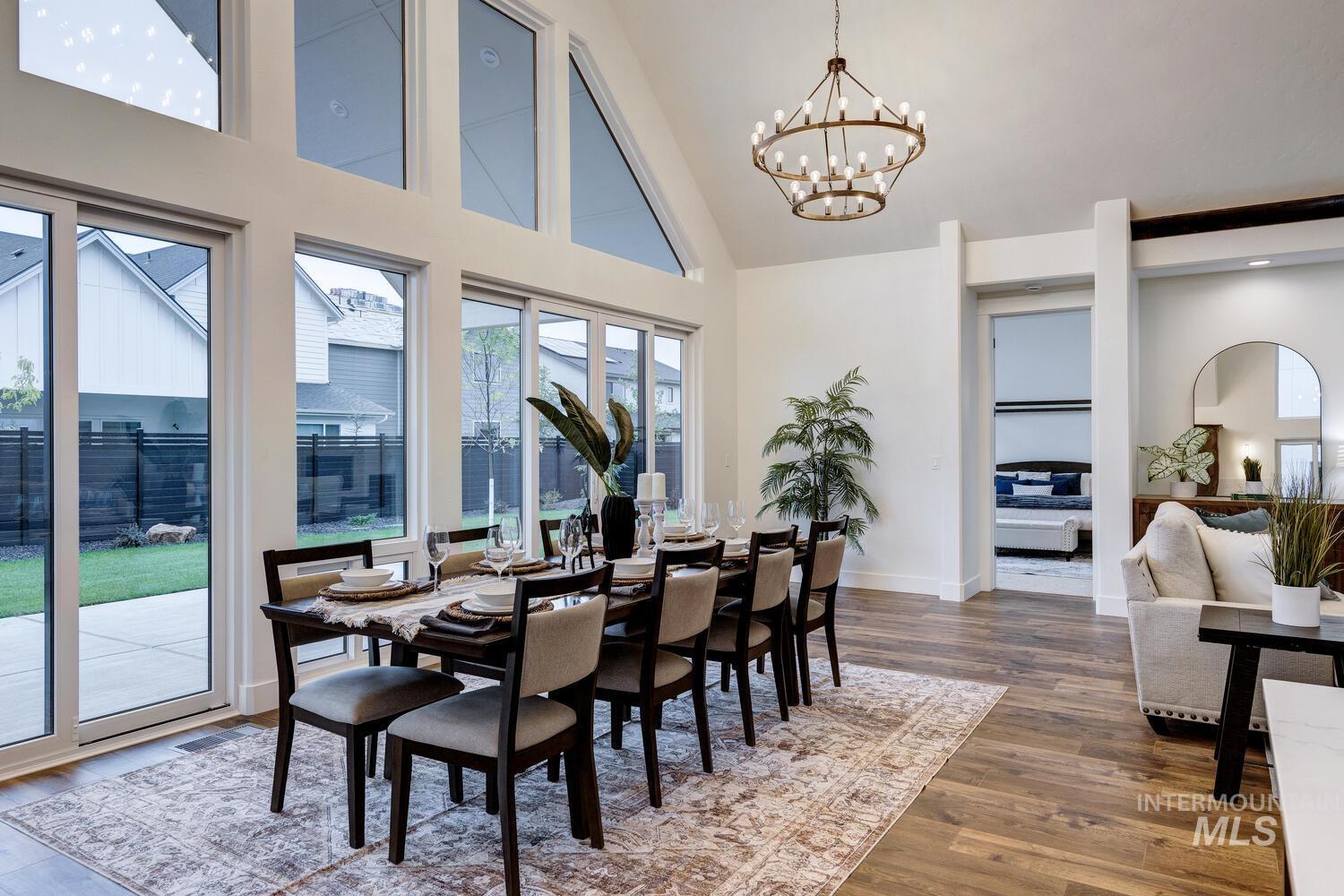 Dining space featuring high vaulted ceiling, wood finished floors, and a chandelier