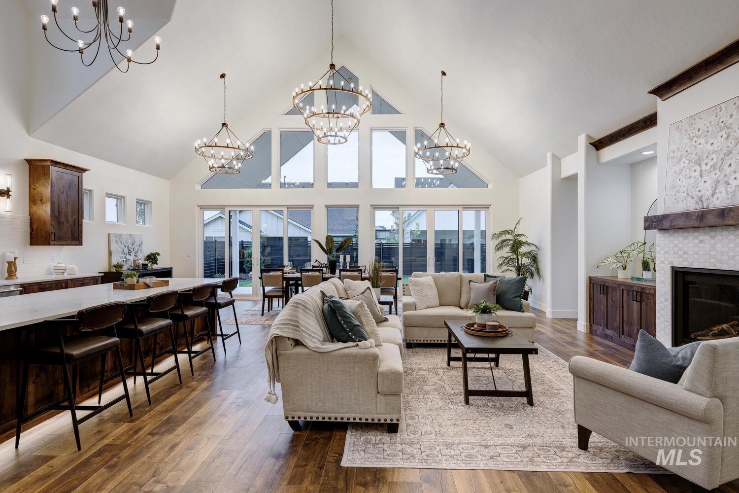 Living room featuring high vaulted ceiling, dark wood finished floors, a glass covered fireplace, and a chandelier