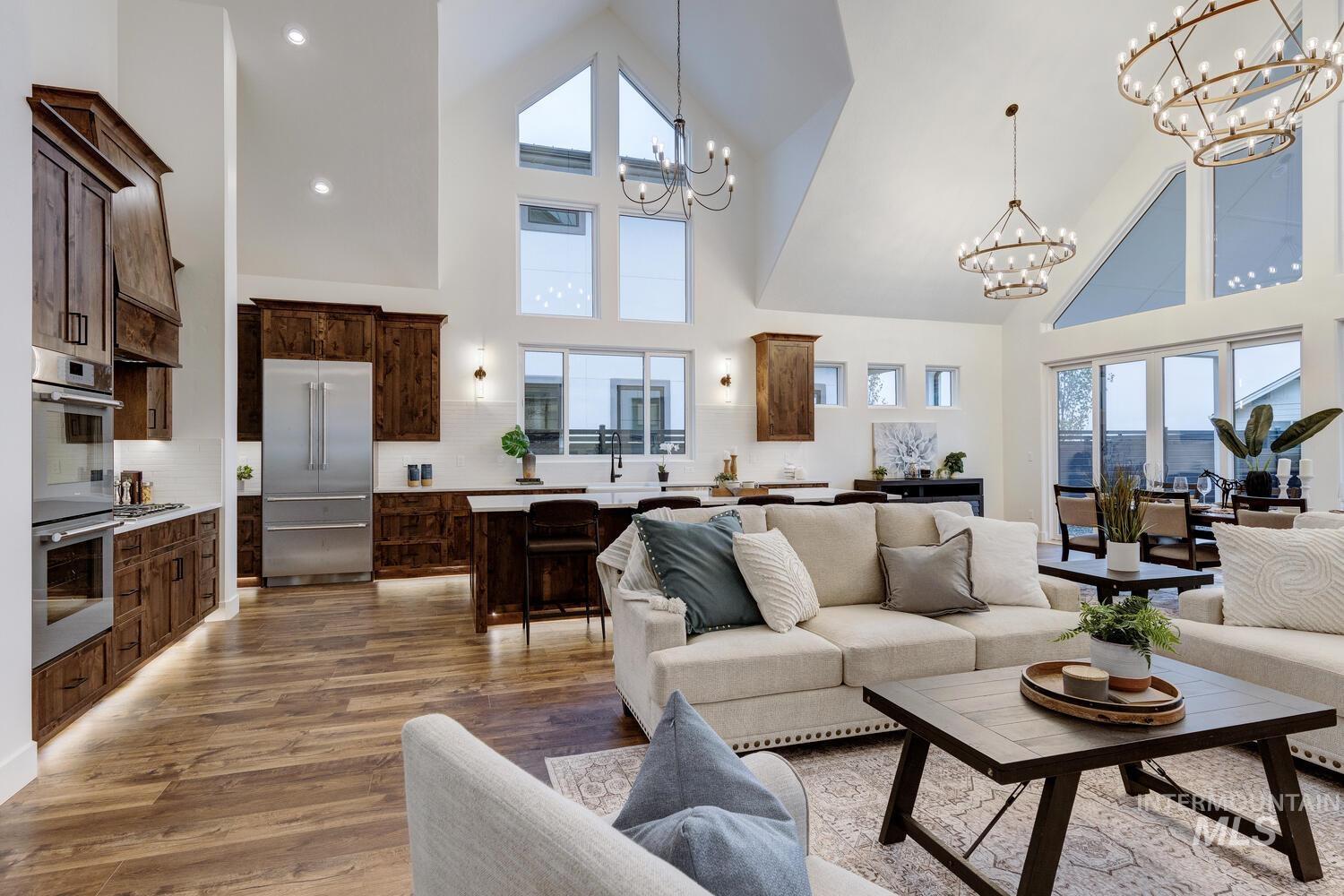 Living area featuring high vaulted ceiling, light wood-style flooring, a chandelier, and recessed lighting
